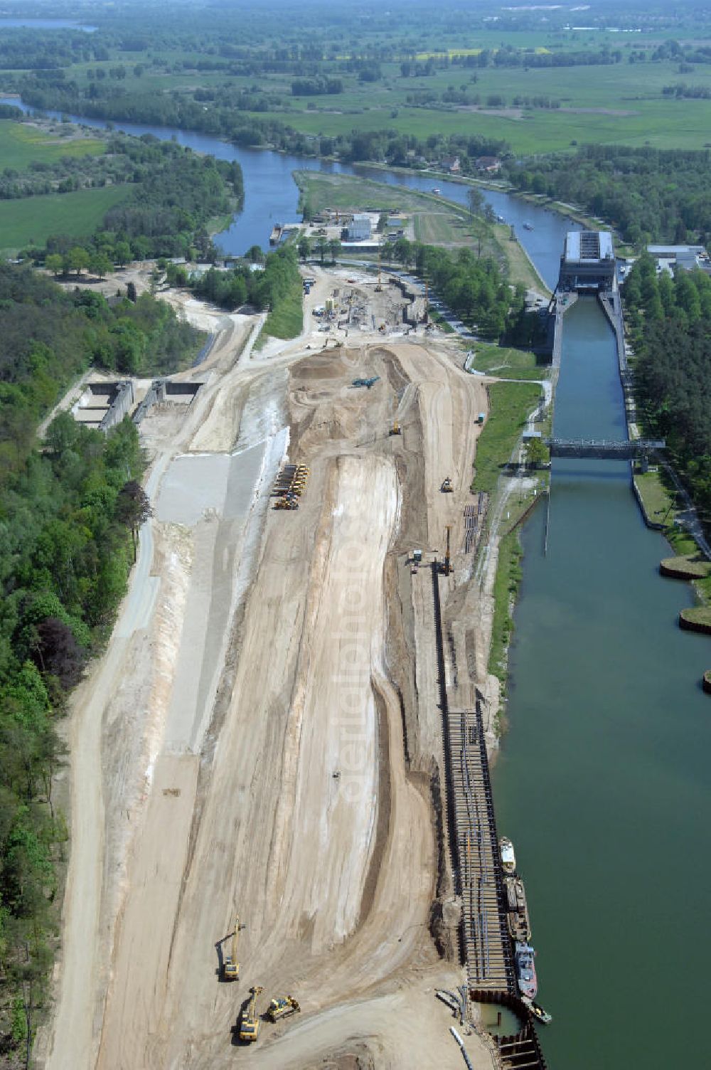 NIEDERFINOW from above - Das Wasserstraßen-Neubauamt Berlin den Bauauftrag für den Neubau des Schiffshebewerkes Niederfinow Nord vergeben. Der Zuschlag wurde auf das Angebot der Bietergemeinschaft Neues Schiffshebewerk Niederfinow unter Federführung der Bilfinger Berger AG erteilt. Der Bietergemeinschaft gehören weiter: die DSD Brückenbau GmbH, die Johann Bunte Bauunternehmung GmbH & Co. KG und die Siemag GmbH an. Die geplante Bauzeit für das neue Schiffshebewerk beträgt fünf Jahre, die Baukosten für die Gesamtanlage liegen bei rd. 285 Mio. Euro und werden durch den Bund finanziert. Seit Mitte Februar 2009 wird die Baugrubenumschließung für das neue Schiffshebewerk hergestellt. Es werden 217 Träger und 214 Zwischenbohlen in den Baugrund eingebracht. Die Träger haben eine Länge von ca. 22m und wiegen einzeln etwa 5,7 Tonnen. Die Rüttelarbeiten für die Baugrube werden voraussichtlich bis Ende April andauern.Mit einem Investitionsvolumen von rd. 285. Mio € entsteht in Niederfinow bis zum Jahr 2014 ein neues Schiffshebewerk der europäischen Wasserstraßenklasse V. Der Neubau ist dringend erforderlich, weil das alte Schiffshebewerk aus dem Jahr 1934 bald das Ende seiner Lebensdauer erreicht hat. Um die Funktion der Havel-Oder-Wasserstraße aufrechtzuerhalten, muss es daher planmäßig durch einen Neubau ersetzt werden.