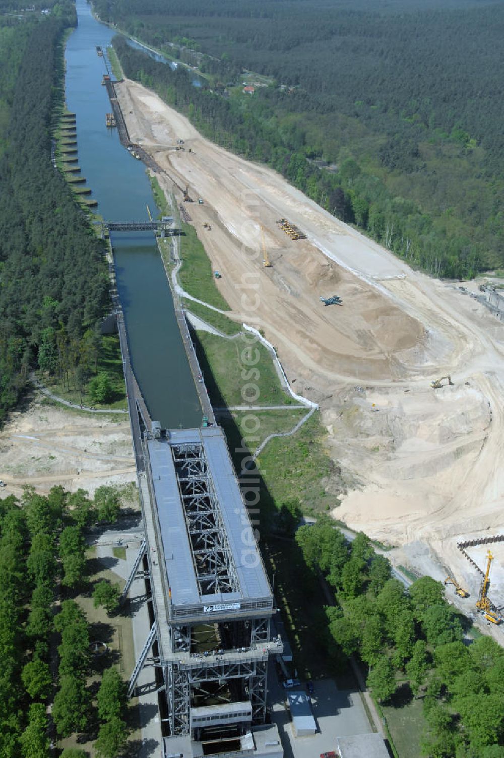 NIEDERFINOW from above - Das Wasserstraßen-Neubauamt Berlin den Bauauftrag für den Neubau des Schiffshebewerkes Niederfinow Nord vergeben. Der Zuschlag wurde auf das Angebot der Bietergemeinschaft Neues Schiffshebewerk Niederfinow unter Federführung der Bilfinger Berger AG erteilt. Der Bietergemeinschaft gehören weiter: die DSD Brückenbau GmbH, die Johann Bunte Bauunternehmung GmbH & Co. KG und die Siemag GmbH an. Die geplante Bauzeit für das neue Schiffshebewerk beträgt fünf Jahre, die Baukosten für die Gesamtanlage liegen bei rd. 285 Mio. Euro und werden durch den Bund finanziert. Seit Mitte Februar 2009 wird die Baugrubenumschließung für das neue Schiffshebewerk hergestellt. Es werden 217 Träger und 214 Zwischenbohlen in den Baugrund eingebracht. Die Träger haben eine Länge von ca. 22m und wiegen einzeln etwa 5,7 Tonnen. Die Rüttelarbeiten für die Baugrube werden voraussichtlich bis Ende April andauern.Mit einem Investitionsvolumen von rd. 285. Mio € entsteht in Niederfinow bis zum Jahr 2014 ein neues Schiffshebewerk der europäischen Wasserstraßenklasse V. Der Neubau ist dringend erforderlich, weil das alte Schiffshebewerk aus dem Jahr 1934 bald das Ende seiner Lebensdauer erreicht hat. Um die Funktion der Havel-Oder-Wasserstraße aufrechtzuerhalten, muss es daher planmäßig durch einen Neubau ersetzt werden.