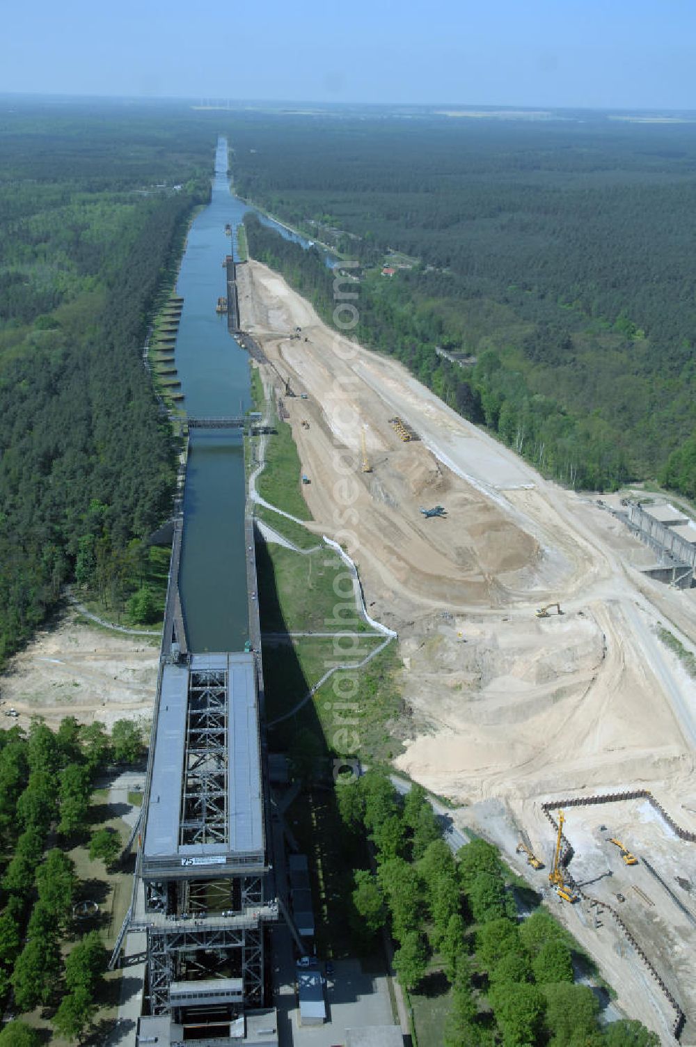 NIEDERFINOW from the bird's eye view: Das Wasserstraßen-Neubauamt Berlin den Bauauftrag für den Neubau des Schiffshebewerkes Niederfinow Nord vergeben. Der Zuschlag wurde auf das Angebot der Bietergemeinschaft Neues Schiffshebewerk Niederfinow unter Federführung der Bilfinger Berger AG erteilt. Der Bietergemeinschaft gehören weiter: die DSD Brückenbau GmbH, die Johann Bunte Bauunternehmung GmbH & Co. KG und die Siemag GmbH an. Die geplante Bauzeit für das neue Schiffshebewerk beträgt fünf Jahre, die Baukosten für die Gesamtanlage liegen bei rd. 285 Mio. Euro und werden durch den Bund finanziert. Seit Mitte Februar 2009 wird die Baugrubenumschließung für das neue Schiffshebewerk hergestellt. Es werden 217 Träger und 214 Zwischenbohlen in den Baugrund eingebracht. Die Träger haben eine Länge von ca. 22m und wiegen einzeln etwa 5,7 Tonnen. Die Rüttelarbeiten für die Baugrube werden voraussichtlich bis Ende April andauern.Mit einem Investitionsvolumen von rd. 285. Mio € entsteht in Niederfinow bis zum Jahr 2014 ein neues Schiffshebewerk der europäischen Wasserstraßenklasse V. Der Neubau ist dringend erforderlich, weil das alte Schiffshebewerk aus dem Jahr 1934 bald das Ende seiner Lebensdauer erreicht hat. Um die Funktion der Havel-Oder-Wasserstraße aufrechtzuerhalten, muss es daher planmäßig durch einen Neubau ersetzt werden.