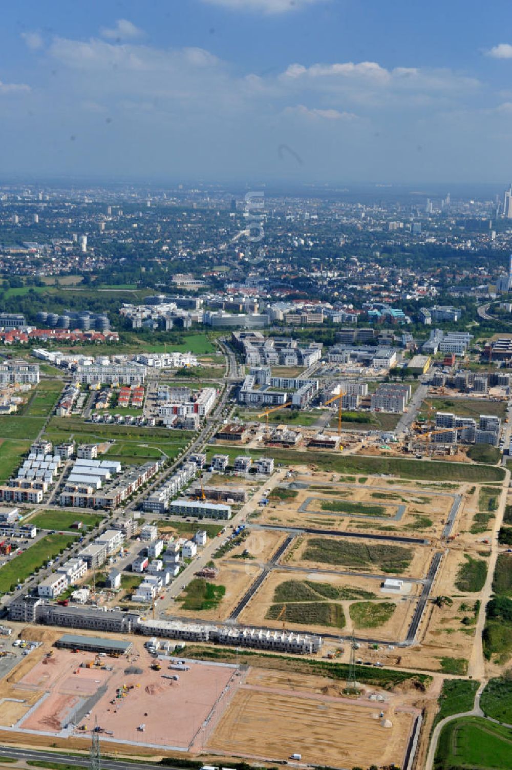 Frankfurt am Main from the bird's eye view: Blick auf das Wohngebiet und die Science City des neu entstehenden Stadtbezirkes Riedberg und das Zentrum von Frankfurt am Main in Hessen. Im Nordwesten der Mainmetropole wächst der neue Stadtteil Riedberg mit Ein- und Mehrfamilienhäusern, Wohnungen, Geschäften, Parks, Restaurants, Büros, Kindereinrichtungen, Schulen, Arztpraxen, Hotels und Dienstleistungsbetrieben. Bis zum Jahr 2017 soll die Großsiedlung ca. 6000 Wohneinheiten mit rund 15.000 Einwohnern haben. In der Riedberger Science City mit dem Universitätscampus der Johann Wolfgang Goethe- Universität und seinen angegliederten Instituten, Zentren und Firmen sollen viele Arbeitsplätze entstehen. Construction of Riedberg district on the outskirts of Frankfurt am Main.