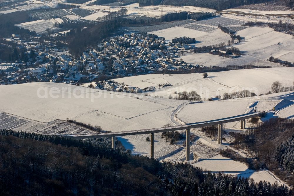 Bestwig from the bird's eye view: Wintry snowy viaduct Nuttlar under construction overlooking the municipality Bestwig in North Rhine-Westphalia