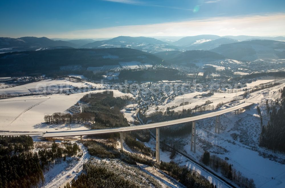 Bestwig from the bird's eye view: Wintry snowy viaduct Nuttlar under construction overlooking the municipality Bestwig in North Rhine-Westphalia