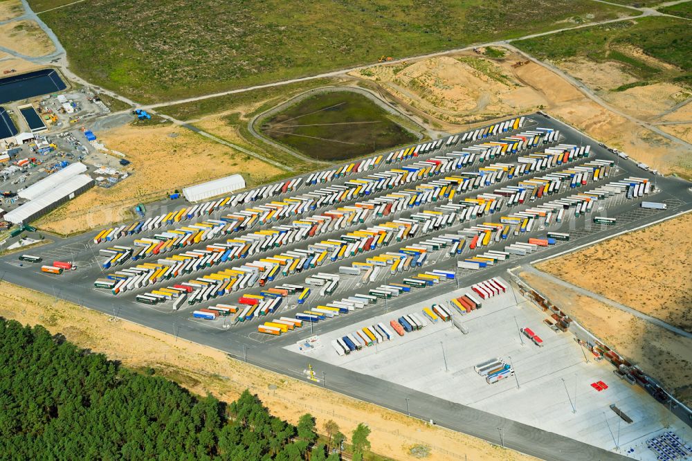 Grünheide (Mark) from the bird's eye view: Truck - semi-trailer wagons for loading and unloading in the parking lot of the Tesla Gigafactory 4 on Schlehenweg - Eichenstrasse in the district of Freienbrink in Gruenheide (Mark) in the federal state of Brandenburg, Germany