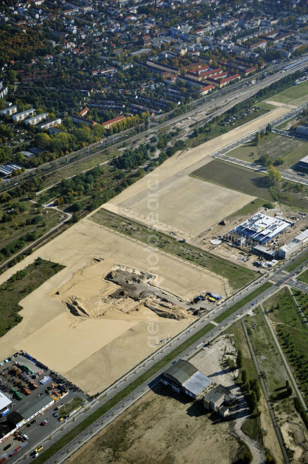 Berlin from the bird's eye view: Blick auf eine Planfläche im Gewerbegebiet Flugplatz Johannisthal am Groß-Berliner Damm. Das Gelände dient heute als Baufläche für Einfamilienhäuser und als Gewerbegebiet. Des weiteren befindet sich heute auf dem Gelände unter an derem der Aerodynamische Park als Teil des Campus der Humboldt-Universität zu Berlin. Der Name des Platzes weist auf den besonderen Charakter und die historische wie architektonische Bedeutung durch die prägnanten und dominierenden Baudenkmale der ehemaligen Deutschen Versuchsanstalt für Luftfahrt e.V. hin. Das mittlerweile entstandene grüne Biotop auf der Fläche der ehemaligen Start- und Landebahn ist in eine Parklandschaft integriert worden, dem Europapark, der nach einem Wettbewerb seit den späten 1990er Jahren hier entsteht. View onto the construction site at the industrial area at the former airport Johannisthal. Today the area serves as ab building area and as an industrial area.