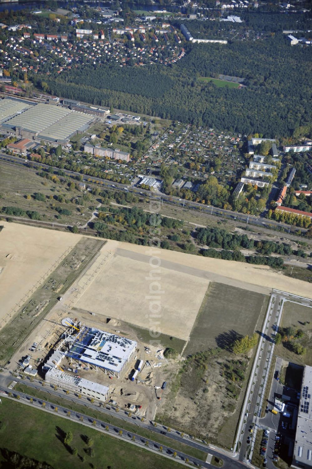 Berlin from above - Blick auf eine Planfläche im Gewerbegebiet Flugplatz Johannisthal am Groß-Berliner Damm. Das Gelände dient heute als Baufläche für Einfamilienhäuser und als Gewerbegebiet. Des weiteren befindet sich heute auf dem Gelände unter an derem der Aerodynamische Park als Teil des Campus der Humboldt-Universität zu Berlin. Der Name des Platzes weist auf den besonderen Charakter und die historische wie architektonische Bedeutung durch die prägnanten und dominierenden Baudenkmale der ehemaligen Deutschen Versuchsanstalt für Luftfahrt e.V. hin. Das mittlerweile entstandene grüne Biotop auf der Fläche der ehemaligen Start- und Landebahn ist in eine Parklandschaft integriert worden, dem Europapark, der nach einem Wettbewerb seit den späten 1990er Jahren hier entsteht. View onto the construction site at the industrial area at the former airport Johannisthal. Today the area serves as ab building area and as an industrial area.