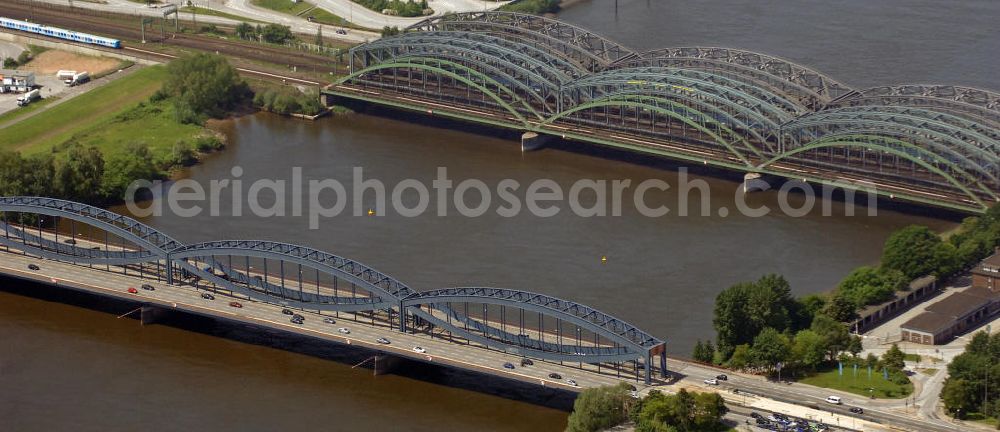 Hamburg from above - Blick auf die Freihafen-Elbrücke, Eisenbahnbrücken und die Neue Elbbrücke (v.l.n.r.). Die Freihafen-Elbbrücke wurde 1929 fertig gestellt, da für den Freihafen eine baulich getrennte Querung der Elbe auch für den Straßenverkehr notwendig war. Die Neue Elbbrücke (rechts) ist die 1990 gebaute erweiterung der Elbbrücke. Die Brücken sind von großer Bedeutung für die Hansestadt, da sie die Verkehrsanbindung Hamburgs über die Elbe gewährleisten. View of the Freihafen-Elbrücke, railway bridges and the Neue Elbbrücke (left to right). The Freihafen-Elbrücke was completed in 1929, because the free port required a structually separated crossing of the Elbe. The new bridge over the Elbe (on the right) is the 1990-built extension to the old bridge over the Elbe. The bridges are of great importance for the Hanseatic city, as they ensure the transport and traffic connection of Hamburg on the Elbe.