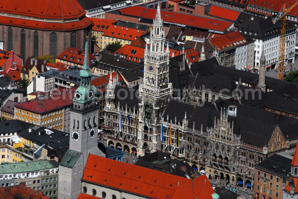 München from the bird's eye view: Blick auf das Neue Rathaus am Marienplatz in München. Das Neue Rathaus in München ist Sitz des Oberbürgermeisters, des Stadtrates und Hauptsitz der Stadtverwaltung. Es wurde von 1867 bis 1909 von Georg von Hauberrisser im neugotischen Stil erbaut. Als die Raumnot im heutigen Alten Rathaus und im 1944 zerstörten Kleinen Rathaus am Petersbergl zu groß wurde, entschlossen sich die Stadtväter zu einem Neubau. In Erinnerung an die einstige bürgerliche Hochblüte während der Gotik entschied man sich für einen neugotischen Neubau. Als Bauplatz wurde die Nordseite des Marienplatzes gewählt, wo noch die Landschaftshäuser standen, die im ausgehenden Mittelalter als eine Art Vertretung der Landschaften gegenüber dem bayerischen Herzog bzw. Kurfürsten errichtet worden waren. 1944 bei Bombenangriffen leicht beschädigt, wurde das Neue Rathaus nach dem Krieg umgebaut. Ende der 1990er Jahre wurde das Neue Rathaus generalsaniert und in Details wieder rekonstruiert, so zum Beispiel das neugotische Ziergeschmiede, welches das Dach krönt. Kontakt: Neues Rathaus, Marienplatz 8, 80331 München, Tel.: 089 / 23300, E-Mail: rathaus@muenchen.de. Im Vordergrund ist die Pfarrkirche St. Peter zu sehen. Die Pfarrkirche Sankt Peter, deren Turm im Volksmund Alter Peter genannt wird und zu Münchens Wahrzeichen zählt, ist die älteste erwähnte Pfarrkirche Münchens und vermutlich der Ursprung Münchens überhaupt. Kontakt: Katholisches Stadtpfarramt St. Peter, Rindermarkt 1, 80331 München, Tel.: 089/2604828, E-Mail: St-Peter.Muenchen@erzbistum-muenchen.de,