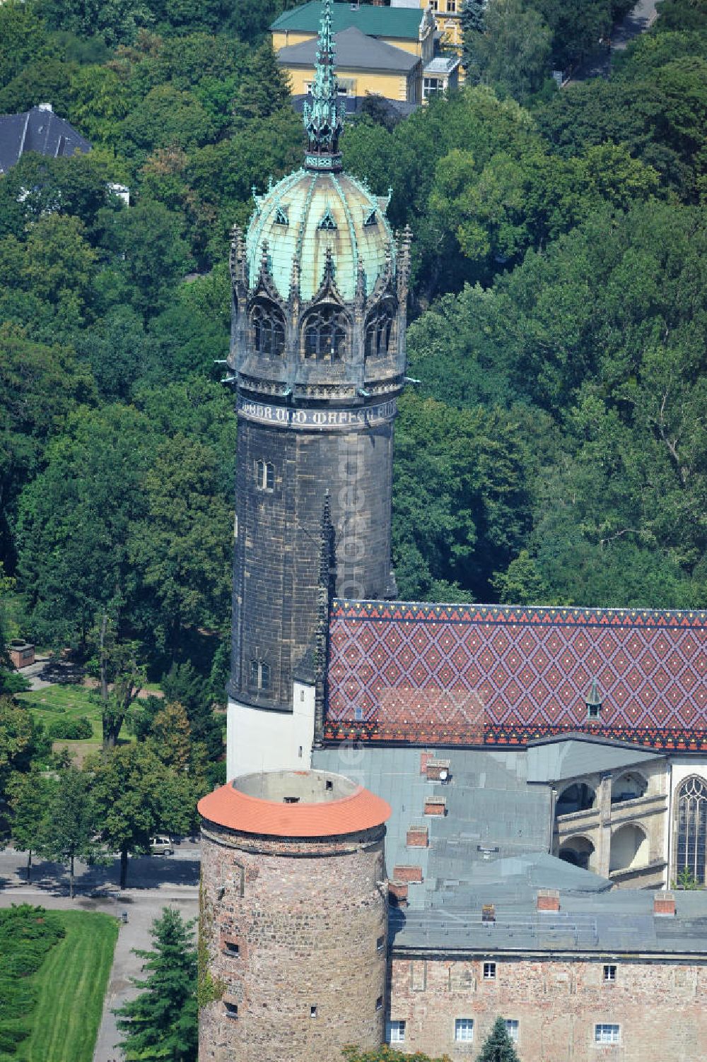 Wittenberg from above - Der Neugotischer Turm der Schlosskirche zu Wittenberg. Das Schloss mit seinem 88 m hohen neugotischen Kirchturm am westlichen Ende der Stadt zählt zum wichtigsten UNESCO-Weltkulturerbe. Die erste Erwähnung der Burg stammt von 1187. Berühmtheit erlangte sie, als am 31. Oktober 1517 der bis dahin nahezu unbekannte Wittenberger Augustinermönch und Theologieprofessor Martin Luther seine 95 lateinischen Disputationsthesen verbreitete. Heute befinden sich im Schloss eine Jugendherberge, das Riemer-Museum und die stadtgeschichtlichen Sammlungen. Tower of the Castle Church of Wittenberg.