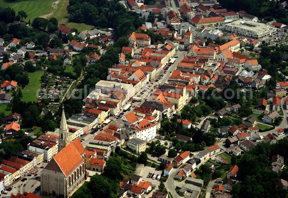 Aerial image Neuötting - Das historische Stadtbild leitet sich direkt von der Topografie ab: auf einem Hochplateau mit steil abfallende Hängen gelegen, folgt der Grundriss der Altstadt dem langgezogenen, in der Mitte aufgeweiteten Marktplatz, an dessen Enden sich jeweils ein Stadttor (Burghauser und Landshuter Tor) befindet. Auf den Marktplatz stoßen von beiden Seiten Gassen, die teilweise durch Schwibbögen vom Platz abgetrennt sind. Die Architektur ist geprägt durch den Inn-Salzach-Stil, der auch in den Altstädten benachbarter Städte, wie etwa Mühldorf a. Inn und Tittmoning, anzutreffen ist. Das Wahrzeichen der Stadt ist die Pfarrkirche St. Nikolaus, eine große dreischiffige Hallenkirche der Spätgotik (1410–1492). Wegen ihrer exponierten Lage am westlichen Ende des Hochplateaus ist sie aus größerer Entfernung sichtbar.Im 13. Jahrhundert wählten die Herzöge von Bayern Neuötting zur Residenzstadt, sie verliehen dem Ort 1321 das Stadtrecht. Neuötting wurde außerdem Sitz einer Münze, die von 1240 bis 1486 bestand. Das Stapelrecht für Salz und Getreide wurde 1649 aufgehoben, was der Wirtschaft und dem Wachstum der Stadt einen Schlag versetzte, von dem sich Neuötting nie mehr erholte. Andere Städte der Region überholten Neuötting, das auf den Status einer Kleinstadt zurückfiel.