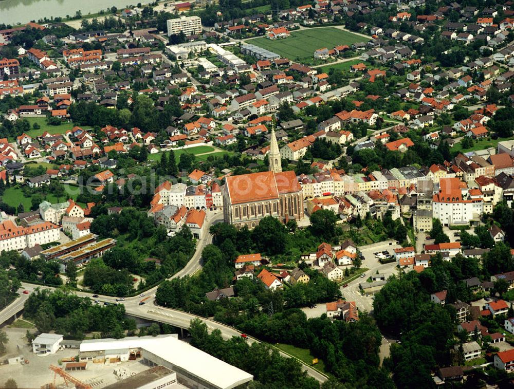 Aerial photograph Neuötting - Das historische Stadtbild leitet sich direkt von der Topografie ab: auf einem Hochplateau mit steil abfallende Hängen gelegen, folgt der Grundriss der Altstadt dem langgezogenen, in der Mitte aufgeweiteten Marktplatz, an dessen Enden sich jeweils ein Stadttor (Burghauser und Landshuter Tor) befindet. Auf den Marktplatz stoßen von beiden Seiten Gassen, die teilweise durch Schwibbögen vom Platz abgetrennt sind. Die Architektur ist geprägt durch den Inn-Salzach-Stil, der auch in den Altstädten benachbarter Städte, wie etwa Mühldorf a. Inn und Tittmoning, anzutreffen ist. Das Wahrzeichen der Stadt ist die Pfarrkirche St. Nikolaus, eine große dreischiffige Hallenkirche der Spätgotik (1410–1492). Wegen ihrer exponierten Lage am westlichen Ende des Hochplateaus ist sie aus größerer Entfernung sichtbar.Im 13. Jahrhundert wählten die Herzöge von Bayern Neuötting zur Residenzstadt, sie verliehen dem Ort 1321 das Stadtrecht. Neuötting wurde außerdem Sitz einer Münze, die von 1240 bis 1486 bestand. Das Stapelrecht für Salz und Getreide wurde 1649 aufgehoben, was der Wirtschaft und dem Wachstum der Stadt einen Schlag versetzte, von dem sich Neuötting nie mehr erholte. Andere Städte der Region überholten Neuötting, das auf den Status einer Kleinstadt zurückfiel.