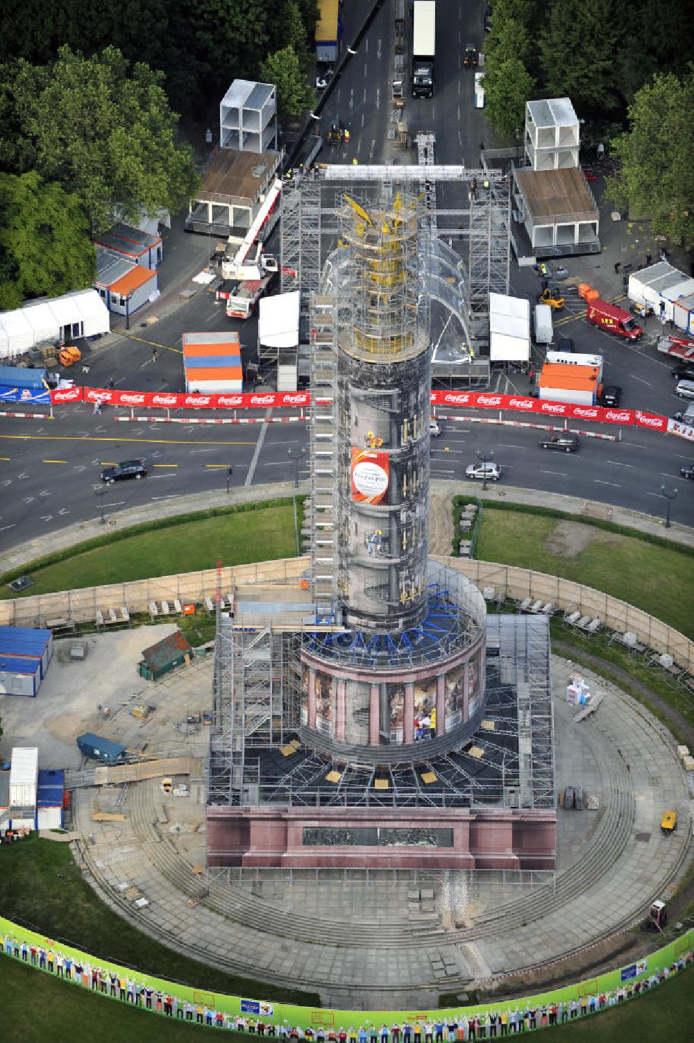 Aerial photograph Berlin - Blick auf die wegen Baumaßnahmen verhüllte und eingerüstete Siegessäule im Berliner Tiergarten. Derzeit wird die Siegessäule umfassend renoviert, unter an derem mit einer kompletten Neuvergoldung der Viktoria. Auf der Straße des 17. Juni ist die Fanmeile zur WM 2010 zu sehen. View of the construction work at the Victory Column in Berlin's Tiergarten. Currently, the Victory Column is completely renovated, including a complete new gilding of Victoria.