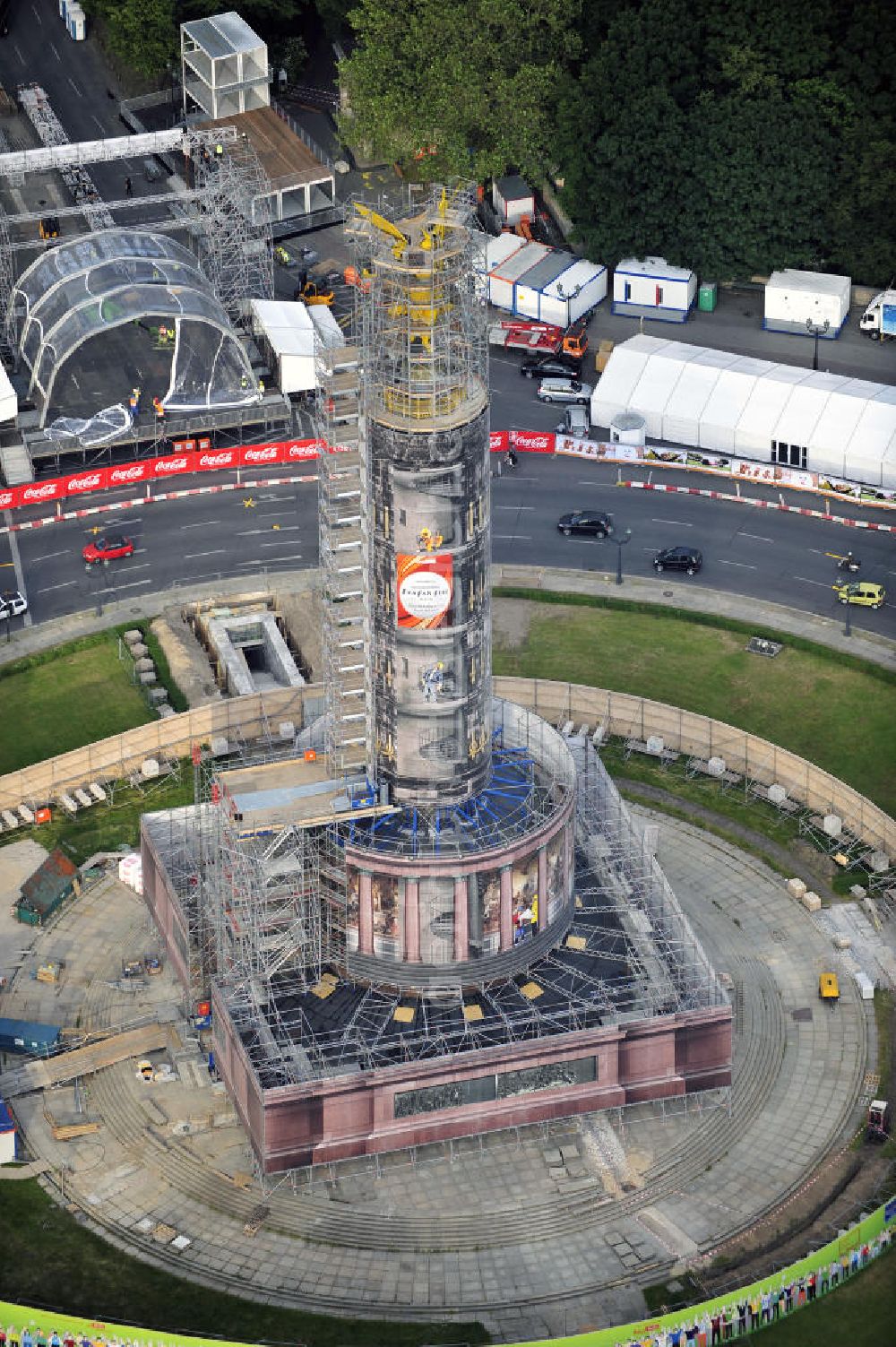 Berlin from the bird's eye view: Blick auf die wegen Baumaßnahmen verhüllte und eingerüstete Siegessäule im Berliner Tiergarten. Derzeit wird die Siegessäule umfassend renoviert, unter an derem mit einer kompletten Neuvergoldung der Viktoria. Auf der Straße des 17. Juni ist die Fanmeile zur WM 2010 zu sehen. View of the construction work at the Victory Column in Berlin's Tiergarten. Currently, the Victory Column is completely renovated, including a complete new gilding of Victoria.