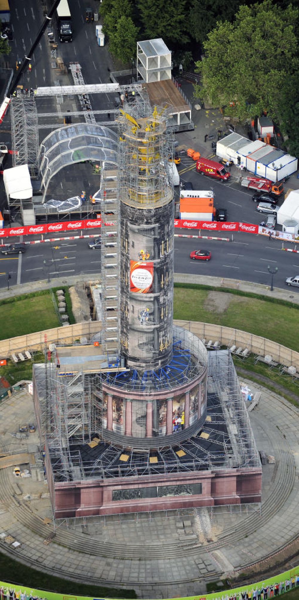 Berlin from the bird's eye view: Blick auf die wegen Baumaßnahmen verhüllte und eingerüstete Siegessäule im Berliner Tiergarten. Derzeit wird die Siegessäule umfassend renoviert, unter an derem mit einer kompletten Neuvergoldung der Viktoria. Auf der Straße des 17. Juni ist die Fanmeile zur WM 2010 zu sehen. View of the construction work at the Victory Column in Berlin's Tiergarten. Currently, the Victory Column is completely renovated, including a complete new gilding of Victoria.