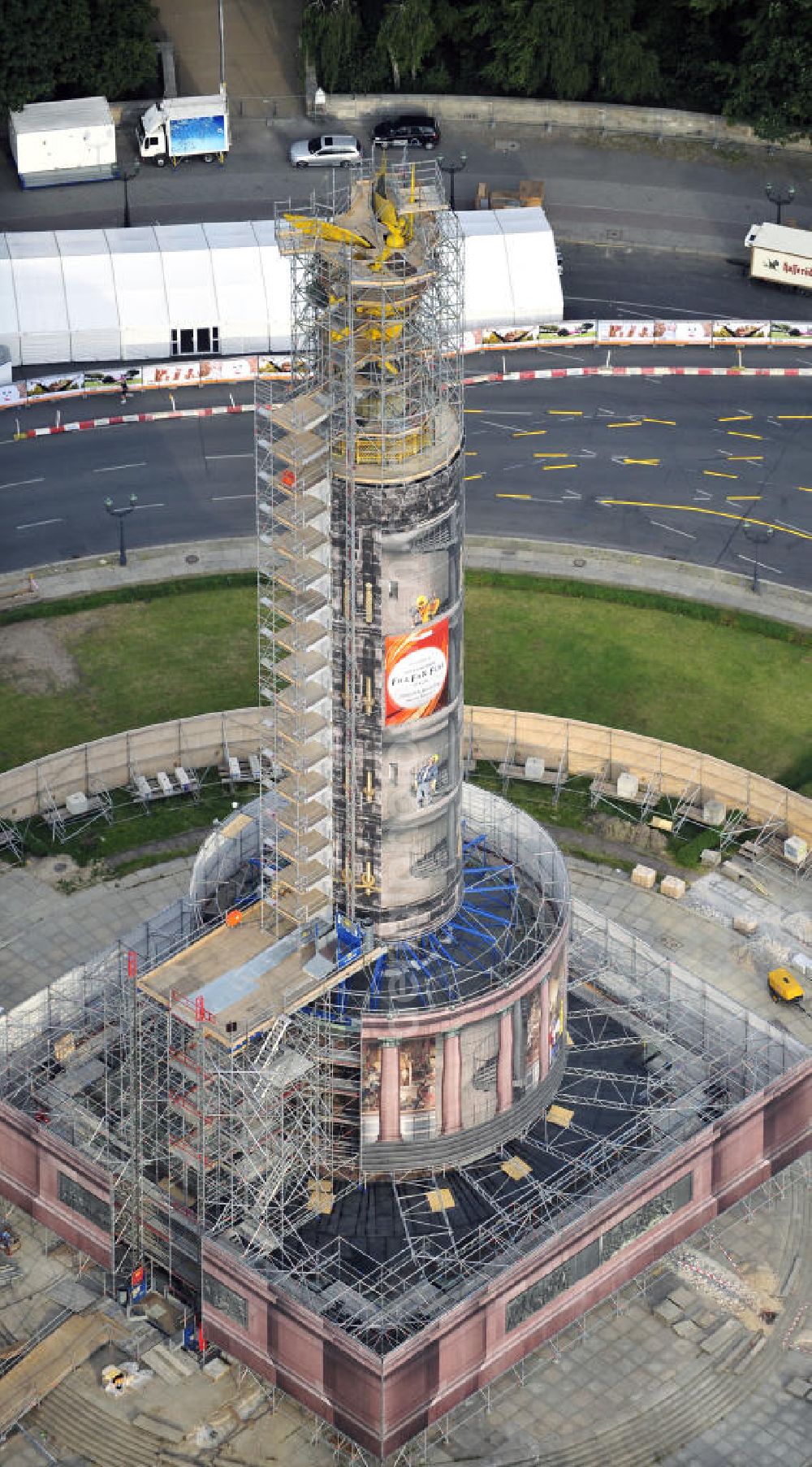 Aerial photograph Berlin - Blick auf die wegen Baumaßnahmen verhüllte und eingerüstete Siegessäule im Berliner Tiergarten. Derzeit wird die Siegessäule umfassend renoviert, unter an derem mit einer kompletten Neuvergoldung der Viktoria. Auf der Straße des 17. Juni ist die Fanmeile zur WM 2010 zu sehen. View of the construction work at the Victory Column in Berlin's Tiergarten. Currently, the Victory Column is completely renovated, including a complete new gilding of Victoria.