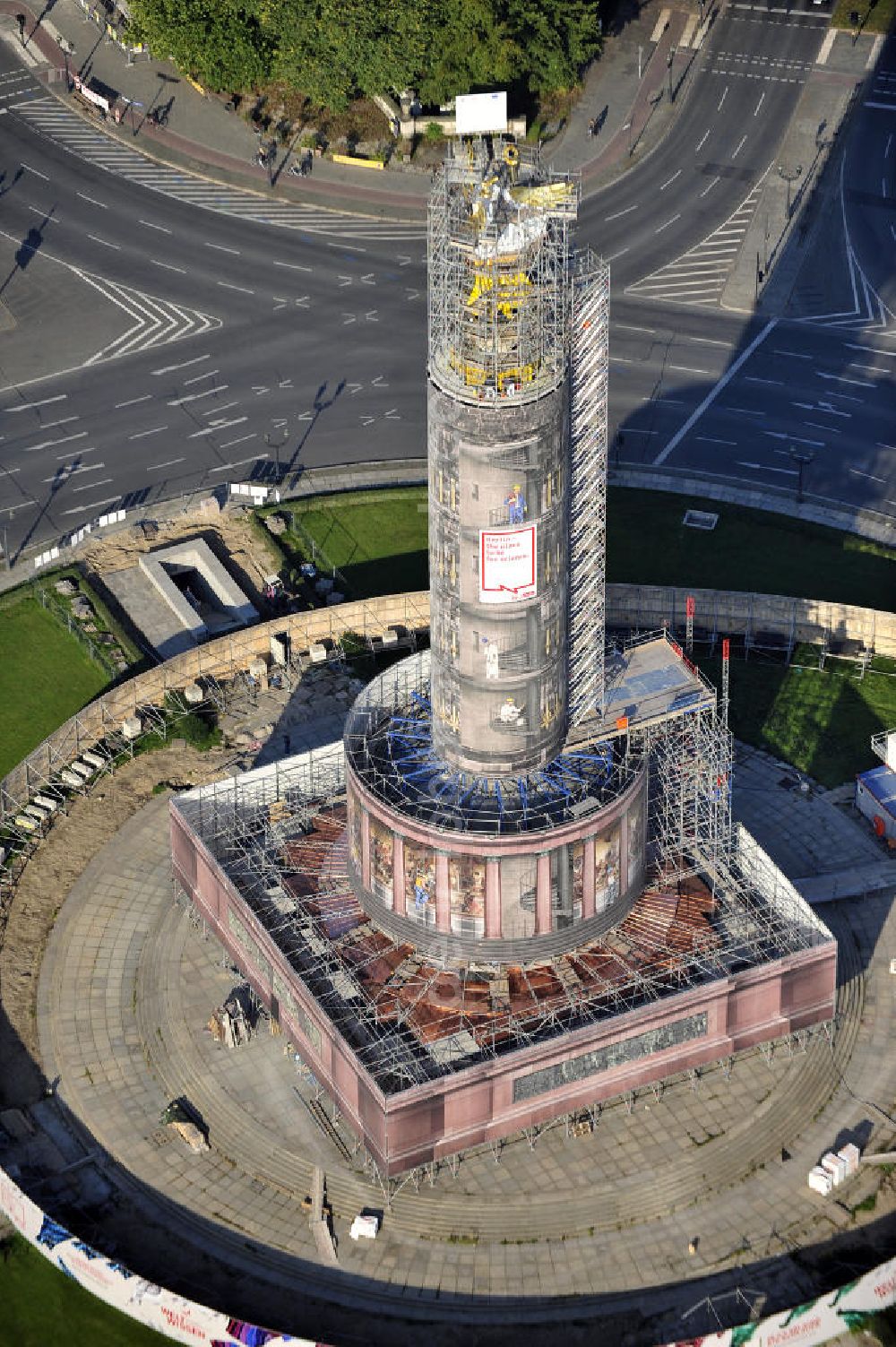 Berlin from the bird's eye view: Blick auf die wegen Baumaßnahmen verhüllte und eingerüstete Siegessäule im Berliner Tiergarten. Derzeit wird die Siegessäule umfassend renoviert, unter an derem mit einer kompletten Neuvergoldung der Viktoria. Auf der Straße des 17. Juni ist die Fanmeile zur WM 2010 zu sehen. View of the construction work at the Victory Column in Berlin's Tiergarten. Currently, the Victory Column is completely renovated, including a complete new gilding of Victoria.