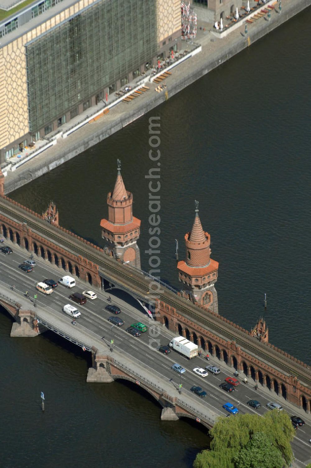 Berlin from the bird's eye view: Die Oberbaumbrücke in Berlin verbindet die Ortsteile Kreuzberg und Friedrichshain über die Spree und liegt zwischen der Elsenbrücke und der Schillingbrücke. Sie ist das Wahrzeichen des Bezirks Friedrichshain-Kreuzberg. Nach der Wiedervereinigung wurde die Brücke für insgesamt 70 Millionen DM umfassend saniert.[3] Für das zerstörte Mittelteil gab es einen internationalen Architektenwettbewerb, aus dem ein Entwurf von Santiago Calatrava als Sieger hervorging. Allerdings erfolgten anschließend recht langwierige Verhandlungen zwischen dem Architekten, den Denkmalschützern, Vertretern der Schifffahrtsbehörde und Experten der Bauämter der beiden damaligen Stadtbezirke, infolgedessen die Pläne von Calatrava mehrfach überarbeitet werden mussten.