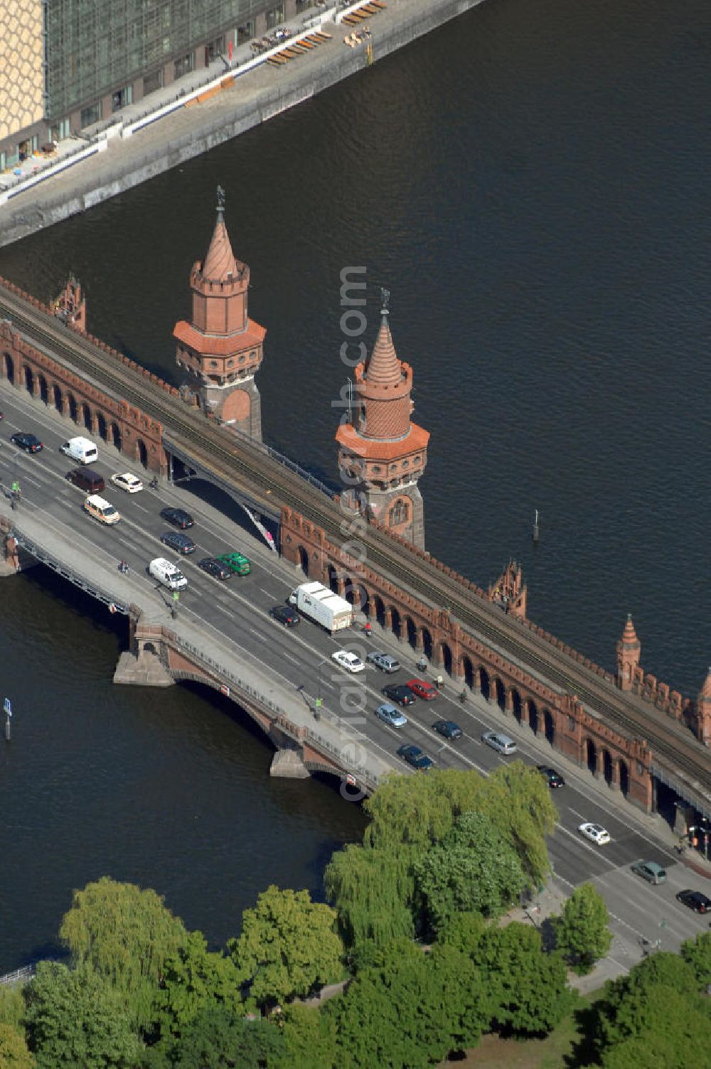 Aerial image Berlin - Die Oberbaumbrücke in Berlin verbindet die Ortsteile Kreuzberg und Friedrichshain über die Spree und liegt zwischen der Elsenbrücke und der Schillingbrücke. Sie ist das Wahrzeichen des Bezirks Friedrichshain-Kreuzberg. Nach der Wiedervereinigung wurde die Brücke für insgesamt 70 Millionen DM umfassend saniert.[3] Für das zerstörte Mittelteil gab es einen internationalen Architektenwettbewerb, aus dem ein Entwurf von Santiago Calatrava als Sieger hervorging. Allerdings erfolgten anschließend recht langwierige Verhandlungen zwischen dem Architekten, den Denkmalschützern, Vertretern der Schifffahrtsbehörde und Experten der Bauämter der beiden damaligen Stadtbezirke, infolgedessen die Pläne von Calatrava mehrfach überarbeitet werden mussten.