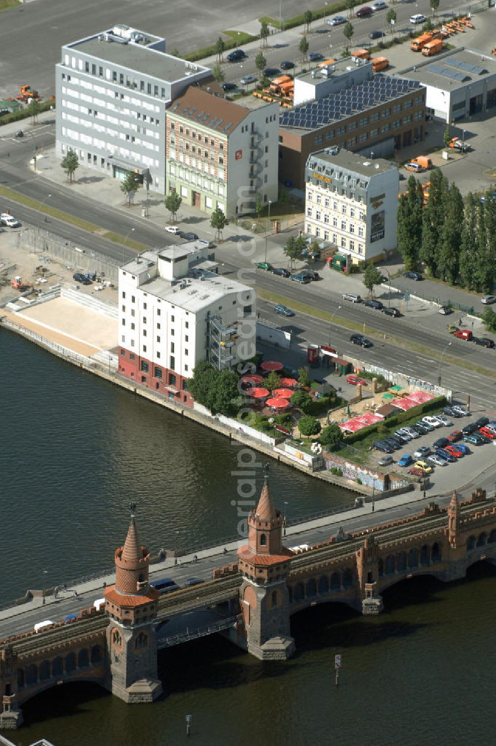 Berlin from the bird's eye view: Die Oberbaumbrücke in Berlin verbindet die Ortsteile Kreuzberg und Friedrichshain über die Spree und liegt zwischen der Elsenbrücke und der Schillingbrücke. Sie ist das Wahrzeichen des Bezirks Friedrichshain-Kreuzberg. Nach der Wiedervereinigung wurde die Brücke für insgesamt 70 Millionen DM umfassend saniert.[3] Für das zerstörte Mittelteil gab es einen internationalen Architektenwettbewerb, aus dem ein Entwurf von Santiago Calatrava als Sieger hervorging. Allerdings erfolgten anschließend recht langwierige Verhandlungen zwischen dem Architekten, den Denkmalschützern, Vertretern der Schifffahrtsbehörde und Experten der Bauämter der beiden damaligen Stadtbezirke, infolgedessen die Pläne von Calatrava mehrfach überarbeitet werden mussten.