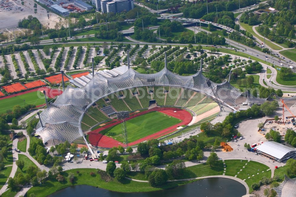 Aerial photograph München - The Olympic Stadium Munich is the central sports venue in the Olympic Park and was capital of the 1972 Summer Olympics in Munich in Bavaria. The group of architects designed the modern Olympic Park Sports facility as part of the landscaping within the meaning of the concept of Olympic Games in the countryside. Thus, the system is designed as a stadium in the ground that is covered by a tent roof. After many years the stadium has been used as a football stadium it now serves mainly as a venue for cultural and athletic events