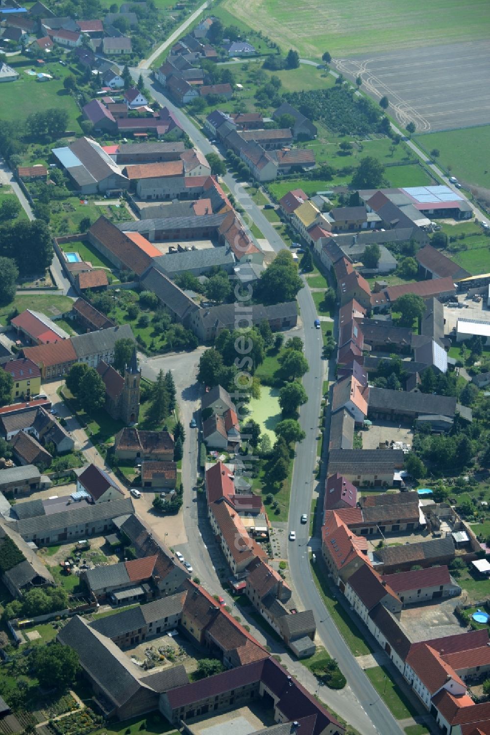 Langenlipsdorf from the bird's eye view: View of the village of Langenlipsdorf in the state of Brandenburg. The village consists of residential houses and agricultural farms and is surrounded by fields. The village church is located on a small pond