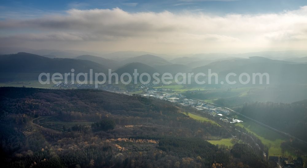 Bremke from the bird's eye view: Location view of the streets and houses of residential areas in the valley landscape surrounded by mountains with fog and cloud layer in Bremke in the state North Rhine-Westphalia, Germany