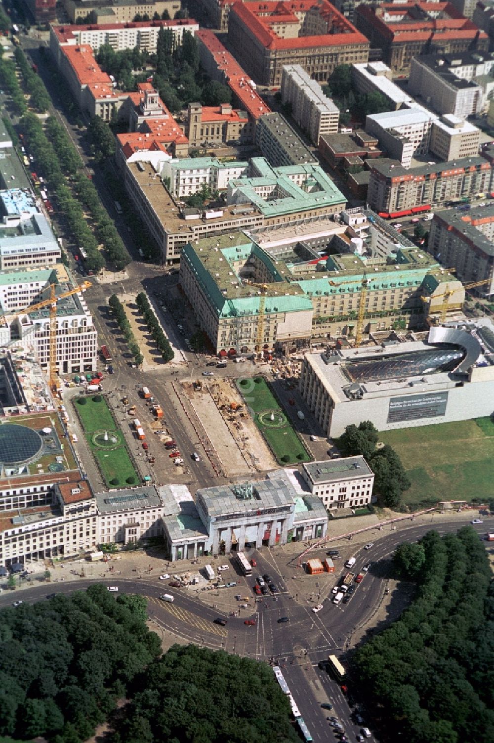 Berlin from above - The Pariser Platz in Berlin-Mitte is the time of recording a construction site. The Brandenburg Gate is covered with a banner. Behind restoration work on the major landmark to be performed. Despite the construction of road leads west through the Brandenburg Gate. About the construction of the French Embassy and the Academy of Arts rotate the cranes