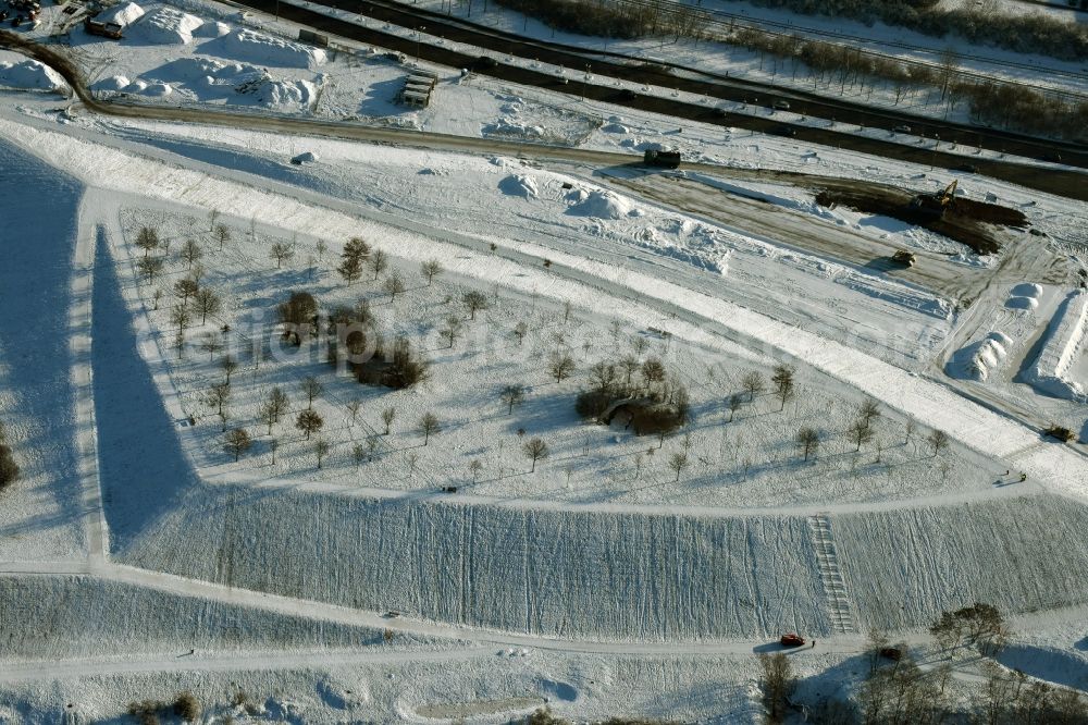 Berlin from the bird's eye view: Winterly snowy area of the park Jelena-Santic-Friedenspark besides the road Hellersdorfer Strasse in Berlin in Germany