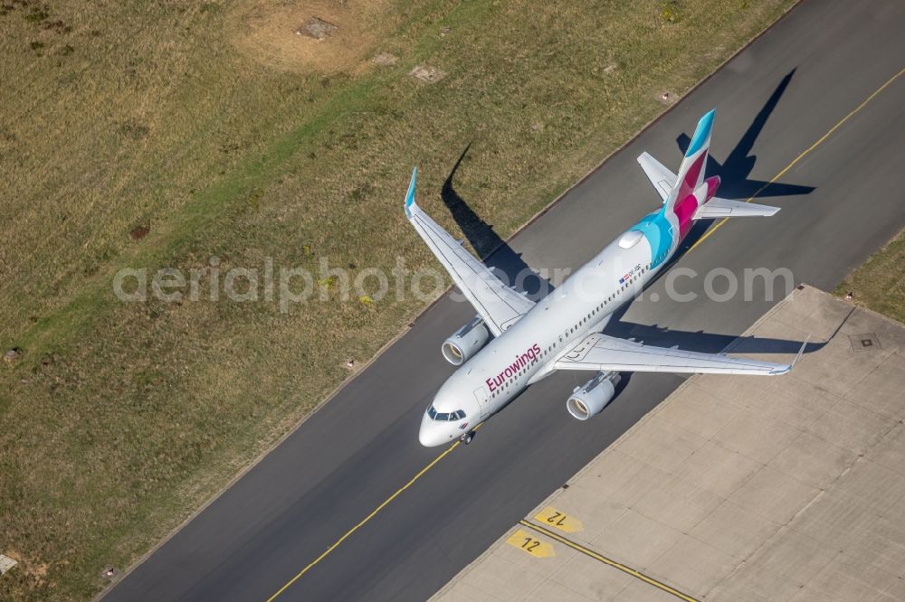 Aerial photograph Holzwickede - Airliner- Passenger aircraft A320-214 operated by eurowings with calling OE-IQC rolling on the apron of the airport in the district Brackel in Holzwickede in the state North Rhine-Westphalia, Germany