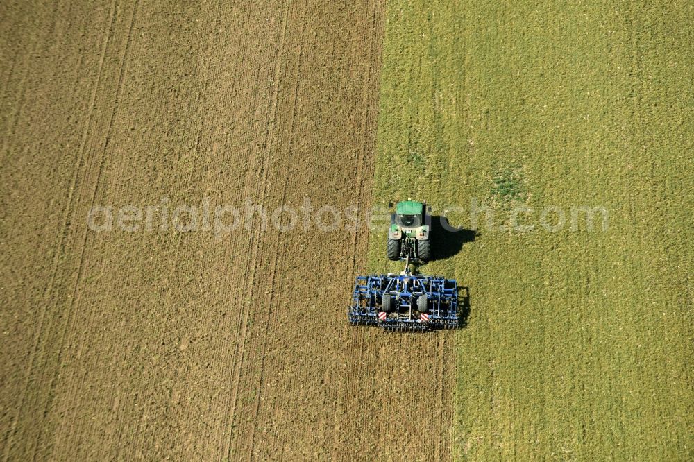 Körlitz from the bird's eye view: Heavy agricultural machinery - plowing vehicle on agricultural fields in Koerlitz in the state of Saxony