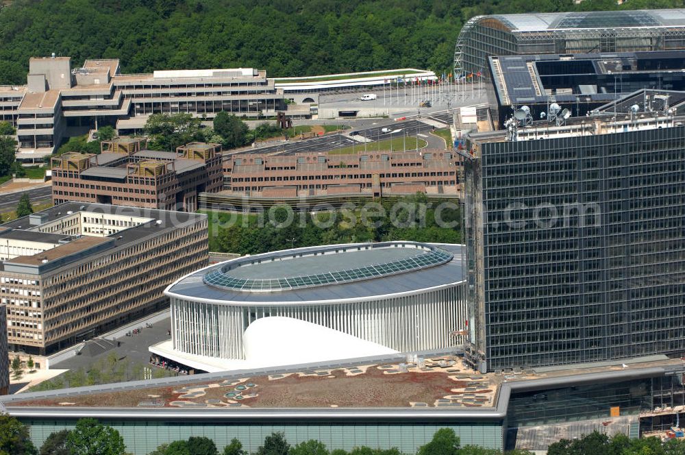 Luxemburg from the bird's eye view: Die Philharmonie Luxembourg ist ein Konzerthaus in der Stadt Luxembourg, sie ist Residenzort des Orchestre Philharmonique du Luxembourg. Das Konzerthaus wurde im Juni 2005 im Stadtteil Kirchberg am Place de l'Europe eröffnet. Architekt ist Christian de Portzamparc, die Ausgestaltung der Akustik im großen Konzertsaal besorgte Albert Yaying Xu. Das weiße Hauptgebäude hat im Grundriss die Form eines Auges; die Stahl-Glas-Fassade wird von 823 weißen Säulen von 20 Metern Höhe und 30 Zentimetern Durchmesser optisch dominiert. Das Konzerthaus hat insgesamt einen umbauten Raum von 192.883 Kubikmetern und eine Gesamtfläche von rund 20.000 Quadratmetern. An der Stahl-Glas-Konstruktion wurden 2.500 Tonnen Baustahl verbaut.