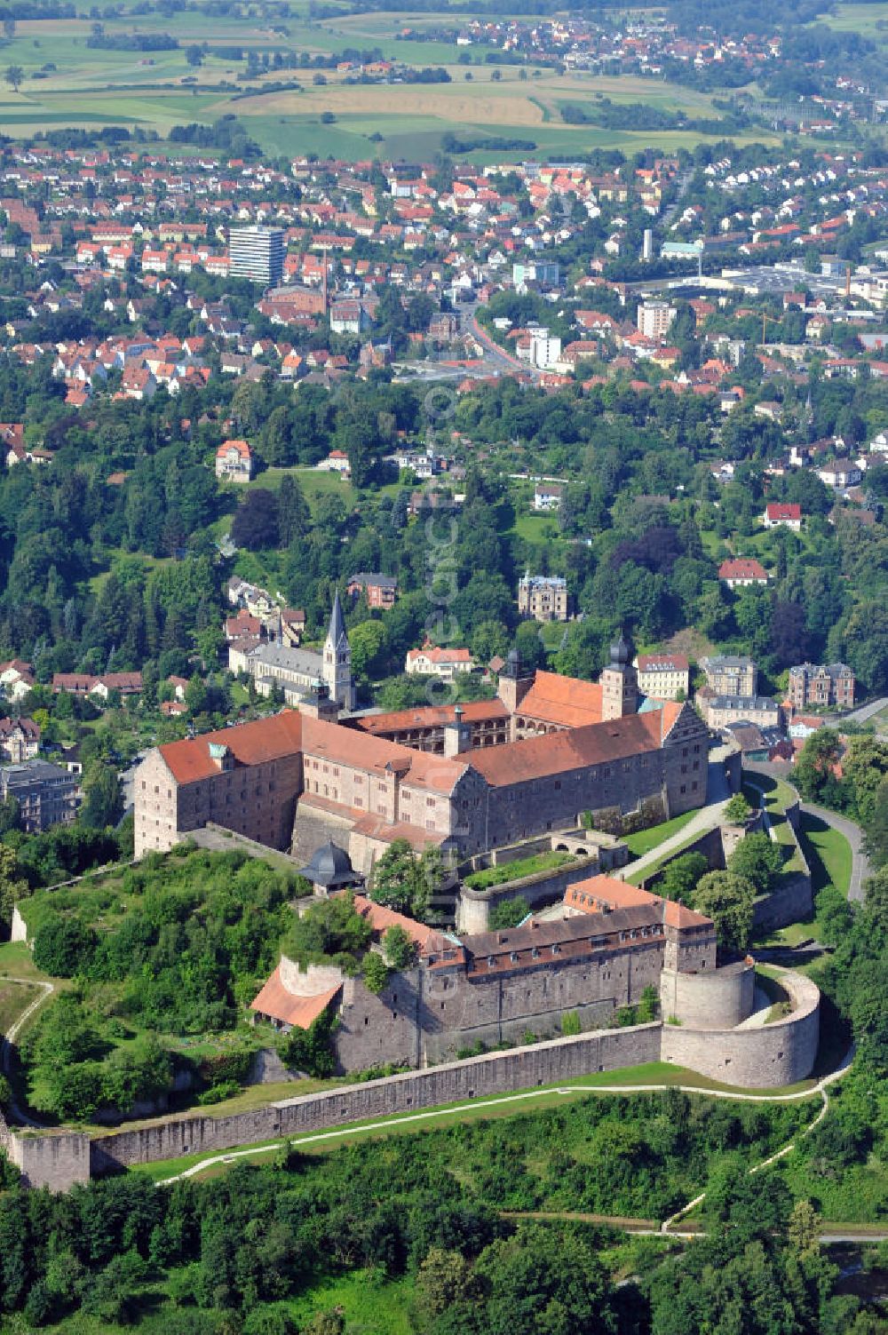 Kulmbach from above - Die Plassenburg in Kulmbach, Bayern. Aufgrund ihrer militärischen Stärke und künstlerischen Ausgestaltung genoss die Burganlage in früheren Jahrhunderten einen fast legendären Ruf. Im dritten Reich beherbergte sie die Reichsschule der deutschen Technik, heutzutage befinden sich hier das staatliche Museum Die Hohenzollern in Franken , das Armeemuseum Friedrich der Große, das Landschaftsmuseum Obermain und das Deutsche Zinnfigurenmuseum. Desweiteren finden auf dem Gelände immer wieder Ausstellungen statt. Es befindet sich im Besitz des Freistaats Bayern. Castle Plassenburg in Kulmbach, Bavaria. Several museums are located here.