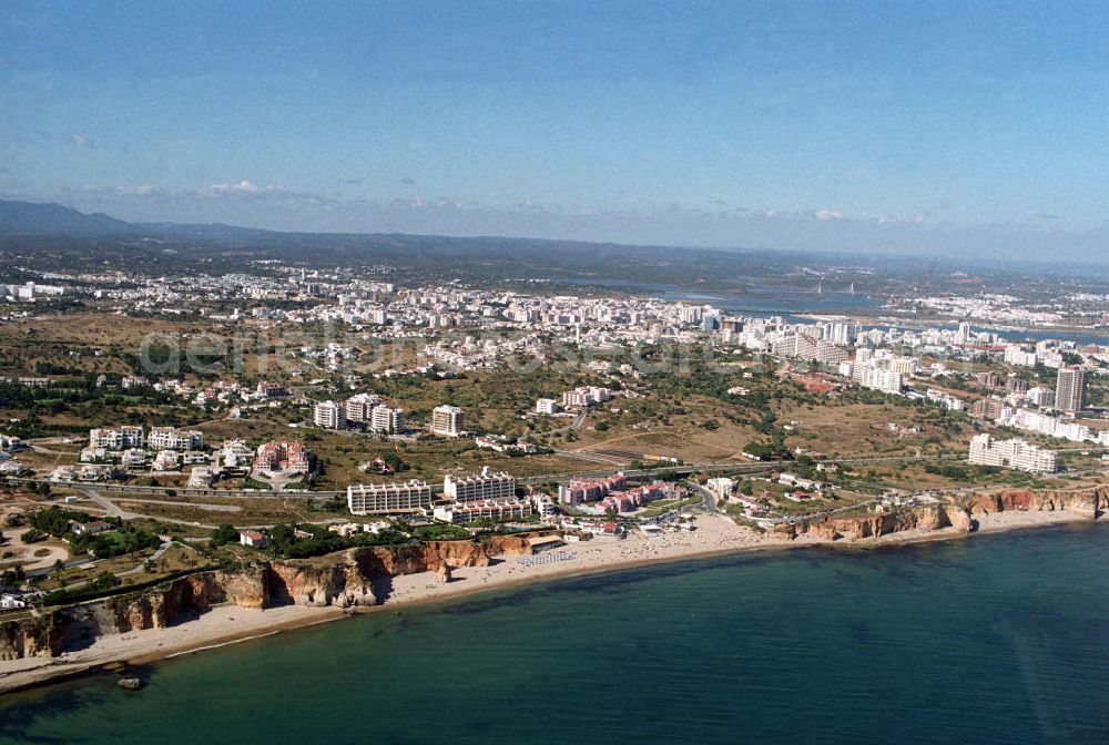 Aerial photograph Praia da Rocha - Blick auf Praia da Rocha, ein beliebter Strand an der Algarve in Portugal. Entstanden ist der ca. 1,5 km lange Küstenabschnitt durch die Meeresauswaschung von härteren Felsgestein aus dem sie umgebendem weicheren Material an der hier ca. 20-30 m hohen Steilküste. Oberhalb der Steilkante haben sich zahlreiche Hotels, Ferienwohnungen, Restaurants und Geschäfte den Standortvorteil gesichert.