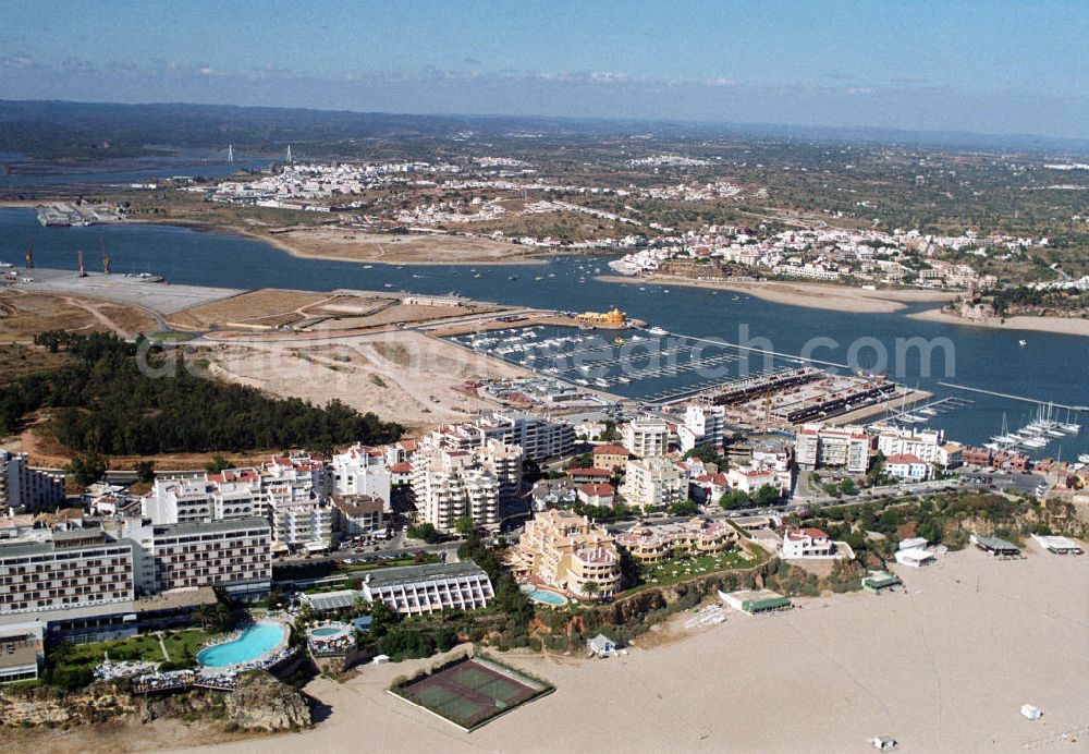 Praia da Rocha from the bird's eye view: Blick auf Praia da Rocha mit dem Yachthafen und im Hintergrund Ferragudo an der Algarve in Portugal. Praia da Rocha ist ein beliebter Badestrand und liegt zwischen Portimao und Alvor. Entstanden ist der ca. 1,5 km lange Küstenabschnitt durch die Meeresauswaschung von härteren Felsgestein aus dem sie umgebenden weicheren Material an der hier ca. 20-30 m hohen Steilküste. Oberhalb der Steilkante haben sich zahlreiche Hotels, Ferienwohnungen, Restaurants und Geschäfte den Standortvorteil gesichert.