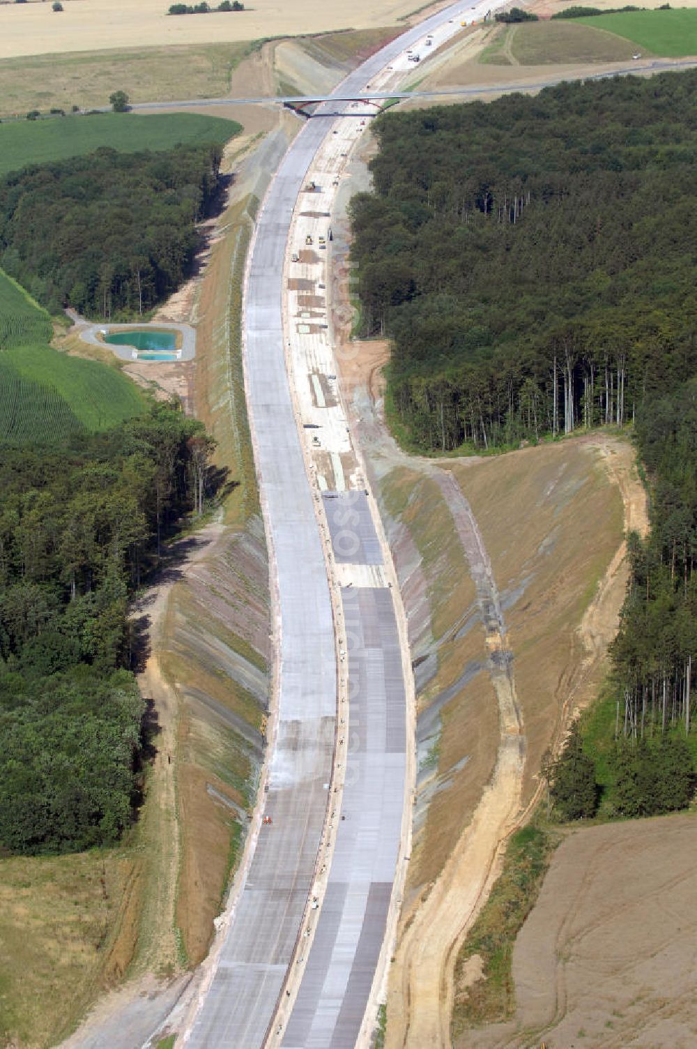 Madelungen from above - Blick auf die Baustelle der A4 entlang des Madelunger Forst mit einem Regenrückhaltebecken, einer Unterführung sowie einer Strassenbrücke südlich von Madelungen. Für die Autobahn wurden in diesem Buchen-Wald ca. 12 Hektar Bäume abgeholzt. Der Neubau ist Teil des Projekt Nordverlegung / Umfahrung Hörselberge der Autobahn E40 / A4 in Thüringen bei Eisenach. Durchgeführt werden die im Zuge dieses Projektes notwendigen Arbeiten unter an derem von den Mitarbeitern der Niederlassung Weimar der EUROVIA Verkehrsbau Union sowie der Niederlassungen Abbruch und Erdbau, Betonstraßenbau, Ingenieurbau und TECO Schallschutz der EUROVIA Beton sowie der DEGES.