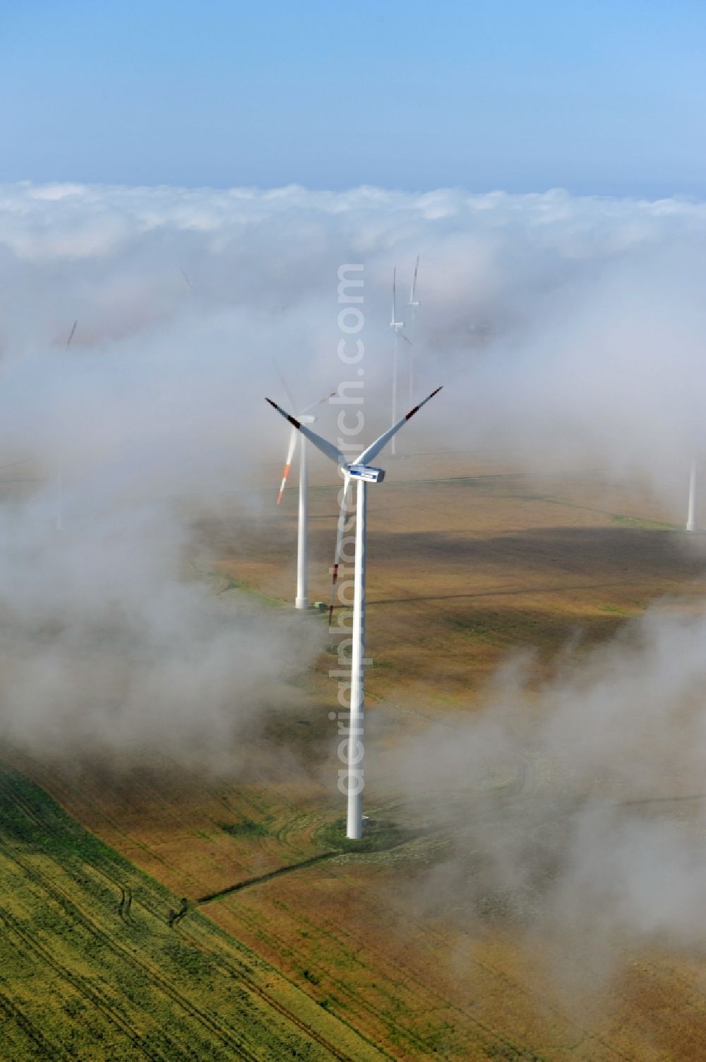 Aerial photograph Werneuchen Ortsteil Seefeld - High fog-like cloud layers imposed by the source view of a wind turbine for electricity generation in the Brandenburg town of Seefeld. The rotors of the Vestas wind turbines stand out from the clouds widely visible