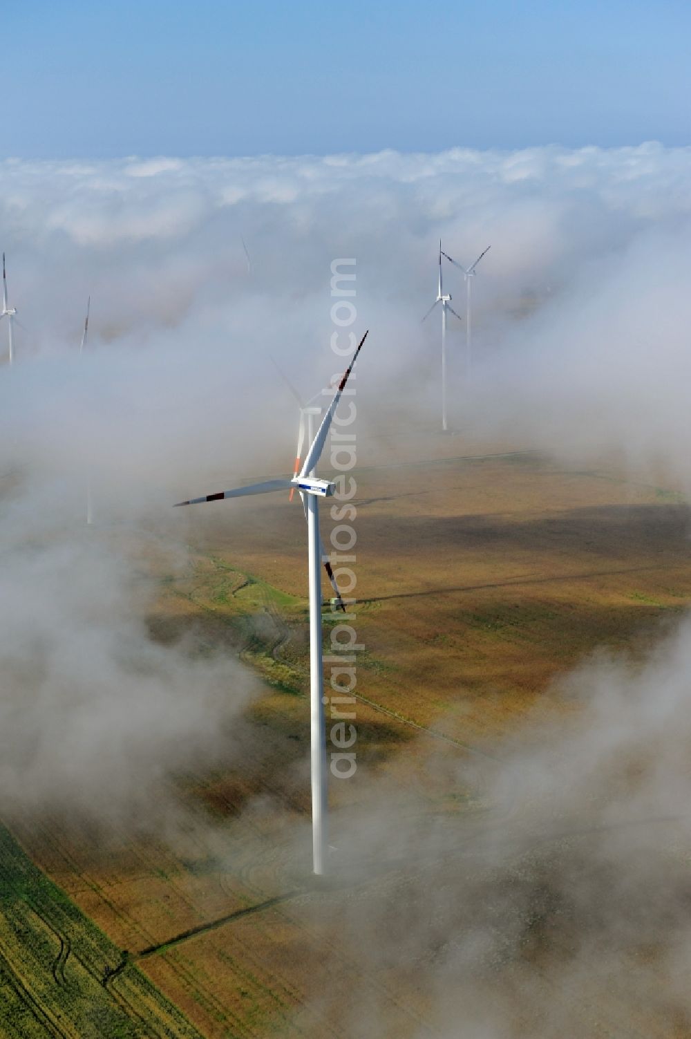 Werneuchen Ortsteil Seefeld from the bird's eye view: High fog-like cloud layers imposed by the source view of a wind turbine for electricity generation in the Brandenburg town of Seefeld. The rotors of the Vestas wind turbines stand out from the clouds widely visible