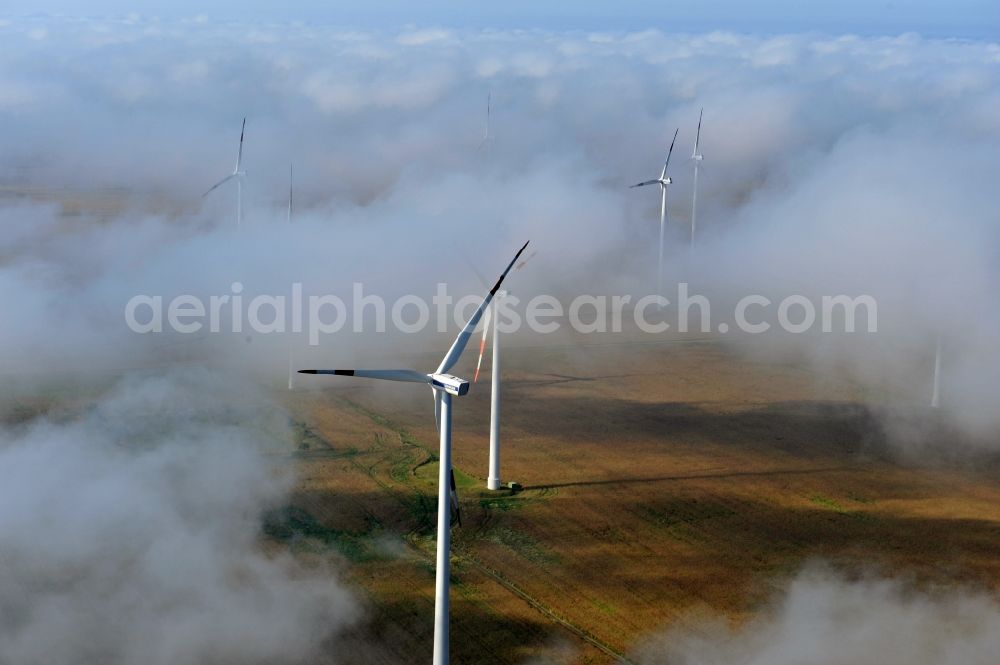 Aerial photograph Werneuchen Ortsteil Seefeld - High fog-like cloud layers imposed by the source view of a wind turbine for electricity generation in the Brandenburg town of Seefeld. The rotors of the Vestas wind turbines stand out from the clouds widely visible