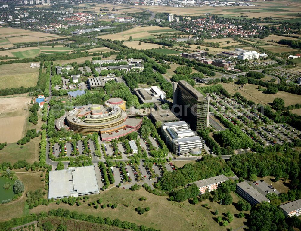 Aerial image MAINZ - Redaktions- und Verwaltungsgebäude des ZDF in Mainz-Lerchenberg. Das ZDF („Zweites Deutsches Fernsehen“) ist eine öffentlich-rechtliche Sendeanstalt in Deutschland und eine der größten Sendeanstalten in Europa. Gemeinsam mit der ARD und dem Deutschlandradio bildet das ZDF den öffentlich-rechtlichen Rundfunk in Deutschland. Hierzu kaufte das ZDF am 25. Juni 1964 ein 1,04 Mio. m² großes, im Mainzer Stadtteil Lerchenberg gelegenes Grundstück. Im ersten Bauabschnitt konnte ein Gebäude für die Übertragungswagen Anfang 1967 bezogen werden; der zweite Abschnitt, das 14-stöckige Redaktions- und Verwaltungsgebäude im Frühjahr 1974. Am 15. September 1977 begannen die Erdarbeiten für den 3. Bauabschnitt des Sendebetriebsgebäudes, einen von der Planungsgruppe Stieldorf, unter an deren von Peter Türler und Wolf Nöhren, entworfenen Rundbau (mit dem größten Durchmesser von 166 Metern). Nach sechsjähriger Bauzeit nahm dann schließlich am 6. Dezember 1984 das neue Sendezentrum (das größte in Europa) seinen Betrieb auf.