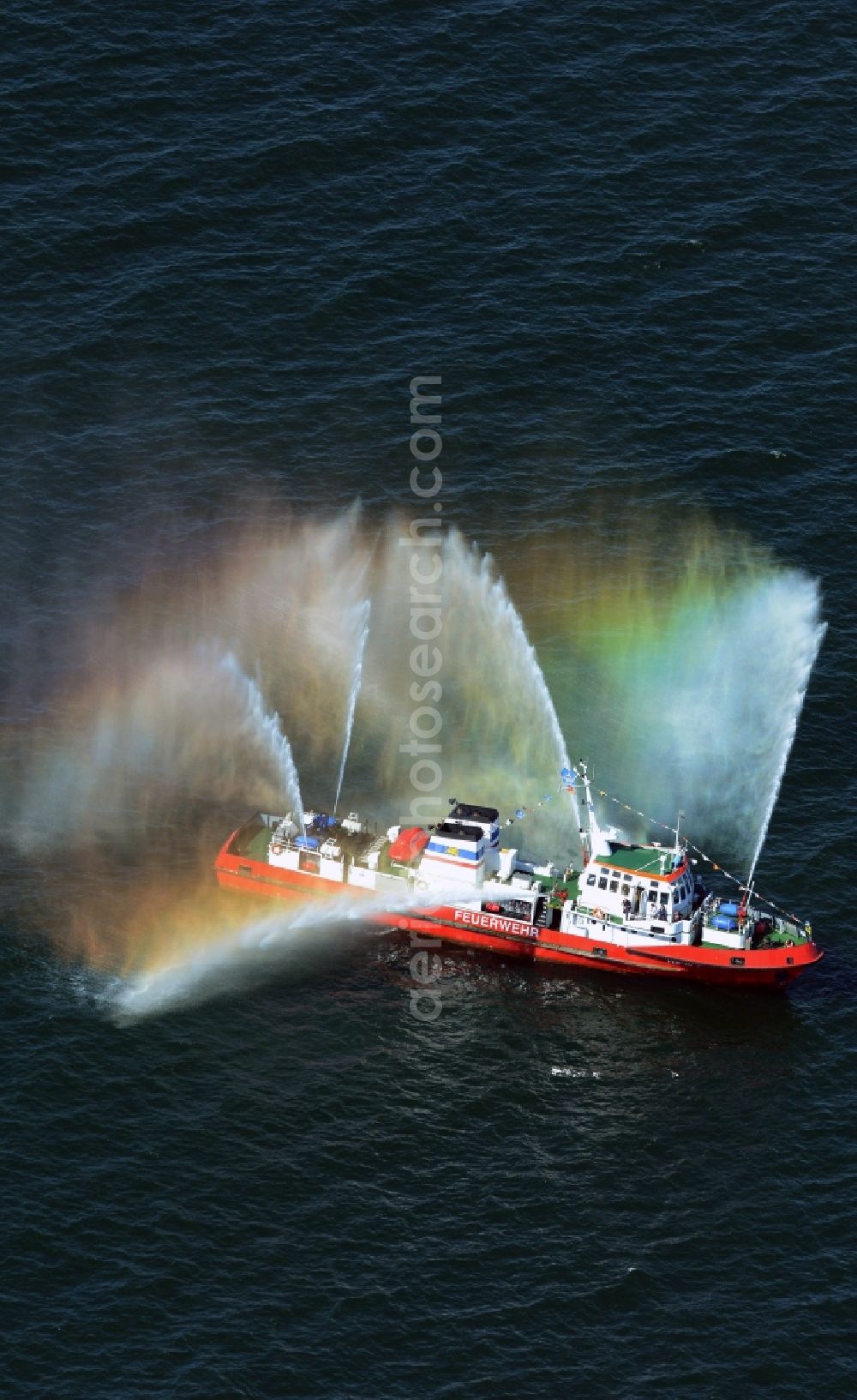 Aerial photograph Rostock - Colorful colored rainbow water fountains of traditional fire extinguishing ship welcoming the sailing ships of the Hanse Sail maritime leak on the Baltic Sea in Rostock in Mecklenburg - Western Pomerania