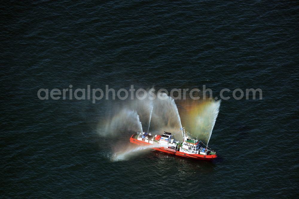 Rostock from above - Colorful colored rainbow water fountains of traditional fire extinguishing ship welcoming the sailing ships of the Hanse Sail maritime leak on the Baltic Sea in Rostock in Mecklenburg - Western Pomerania