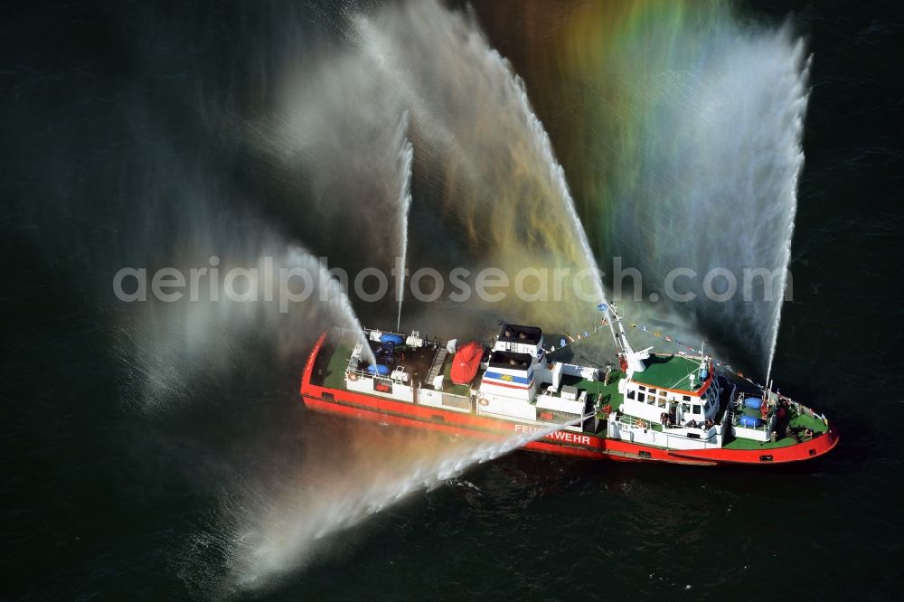 Aerial photograph Rostock - Colorful colored rainbow water fountains of traditional fire extinguishing ship welcoming the sailing ships of the Hanse Sail maritime leak on the Baltic Sea in Rostock in Mecklenburg - Western Pomerania