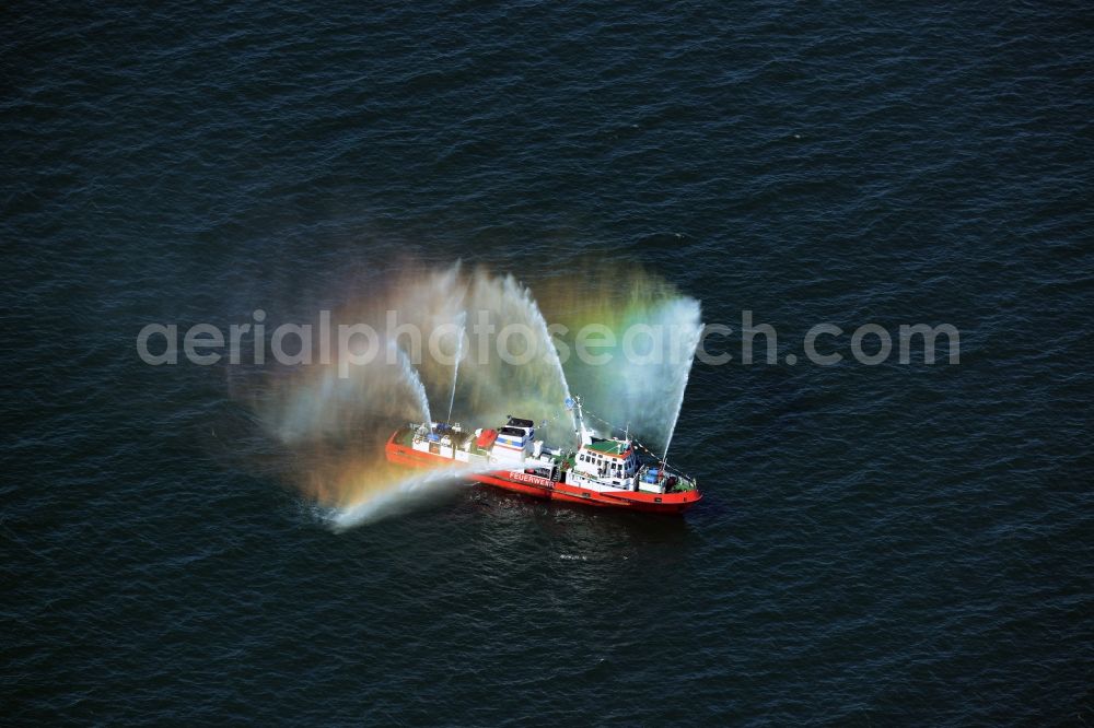 Rostock from the bird's eye view: Colorful colored rainbow water fountains of traditional fire extinguishing ship welcoming the sailing ships of the Hanse Sail maritime leak on the Baltic Sea in Rostock in Mecklenburg - Western Pomerania