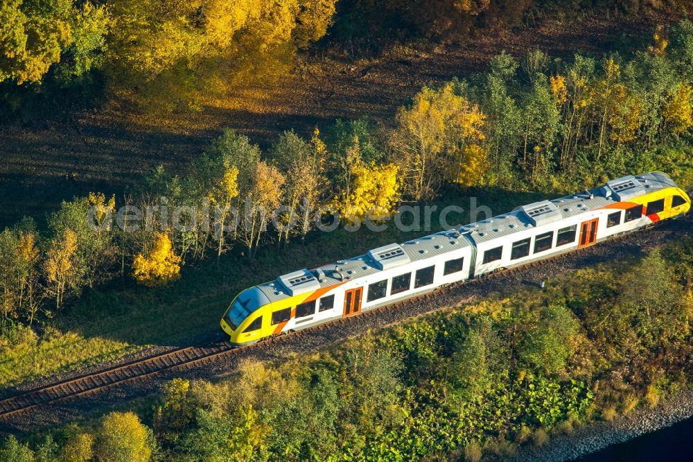 Finnentrop from the bird's eye view: Regional train of HLB rail line in an autumnal forest in the Southwest of Finnentrop in the state of North Rhine-Westphalia