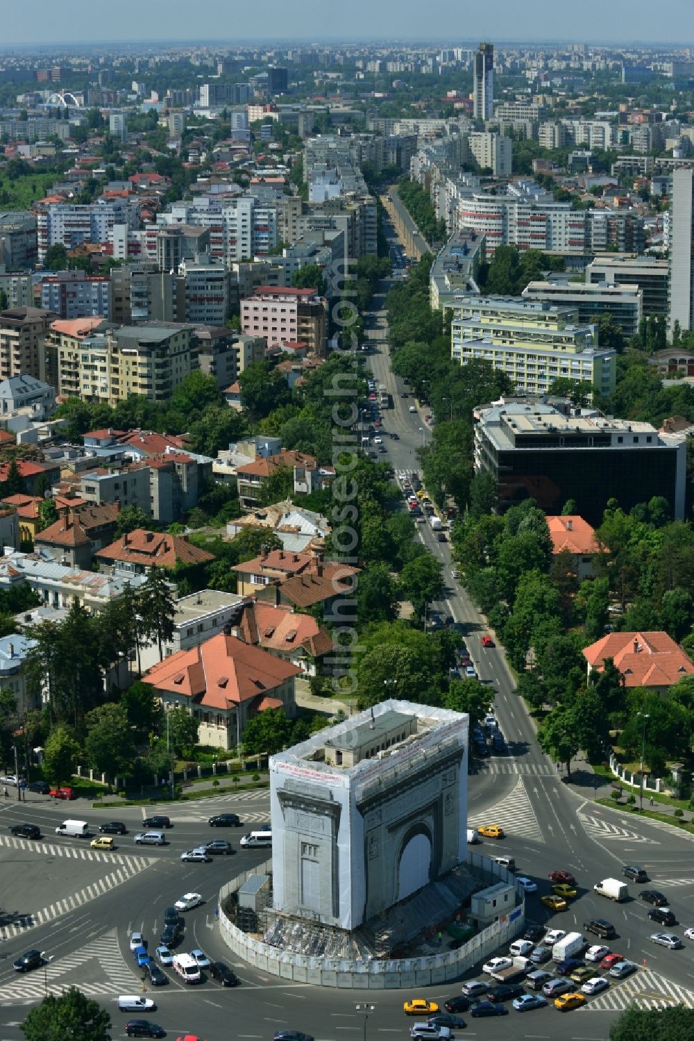 Bukarest from above - The restoration and rehabilitation work on the Arcul de Triumf, the triumph arch in the Romanian capital Bucharest in Romania. The landmark on the star-shaped roundabout tapering of Piata Arcul de Triumf is currently covered with a to-scale printed tarpaulin to protect the sandblasting and restoration work