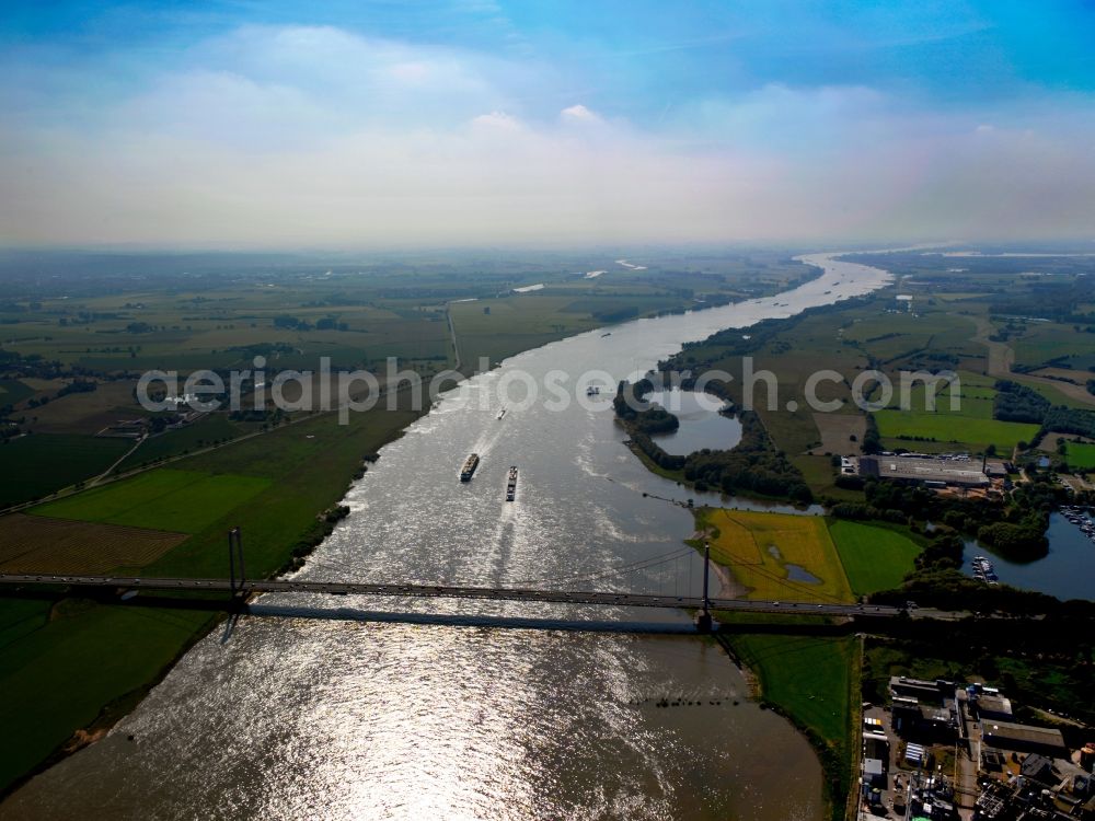 Emmerich am Rhein from the bird's eye view: The Rhine bridge and container ships on the river Rhine in the city of Emmerich on Rhine in the state of North Rhine-Westphalia. The river marks the border to the Netherlands. Cargo shipping is especially important in the area, the metropolitan area also includes the Rhine port. The bridge is Germany's longest suspension bridge