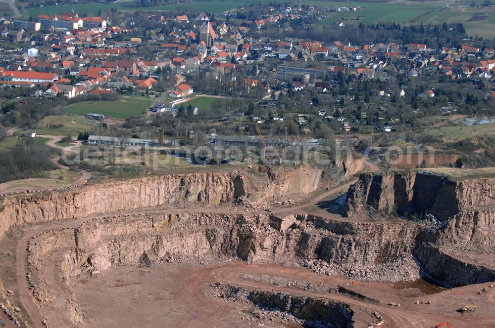 Aerial photograph Löbejün - Blick auf den Rhyolithsteinbruch / Steinbruch Löbejün. Hier wird der Löbejüner Porphyr bzw. Quarzporphyr (exakte petrographische Bezeichnung: Rhyolith) ein Vulkanit von rötlicher Farbe abgebaut. Seit 1518 wirde in Löbejün Porphyr abgebaut. Im Hintergrund die Stadt Löbejün. Kontakt: SH Natursteine GmbH & Co. KG, Bahnhofstraße 7, 06193 Löbejün, Tel. +49(0)34603 75 0, Fax +49(0)34603 75 149