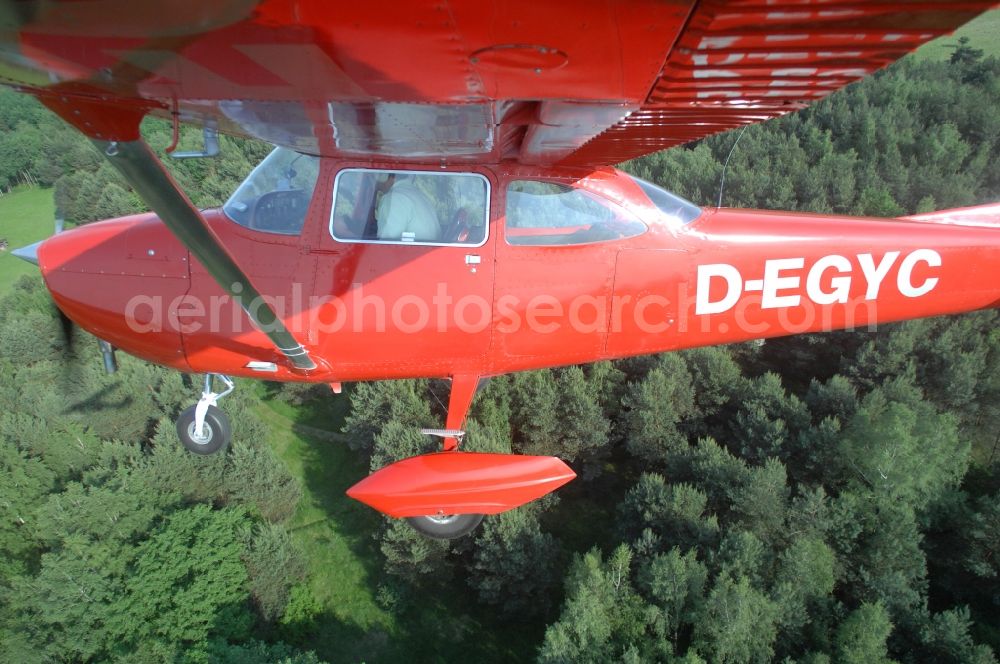 Werneuchen from the bird's eye view: Bright red Cessna 172 D-EGYC of the agency euroluftbild.de in flight over the airfield in Werneuchen in the state Brandenburg, Germany