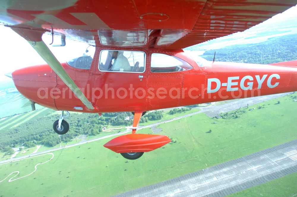 Werneuchen from the bird's eye view: Bright red Cessna 172 D-EGYC of the agency euroluftbild.de in flight over the airfield in Werneuchen in the state Brandenburg, Germany