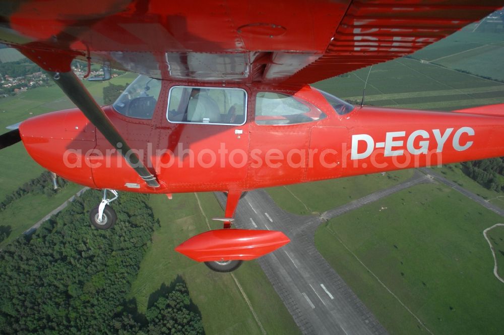 Werneuchen from the bird's eye view: Bright red Cessna 172 D-EGYC of the agency euroluftbild.de in flight over the airfield in Werneuchen in the state Brandenburg, Germany