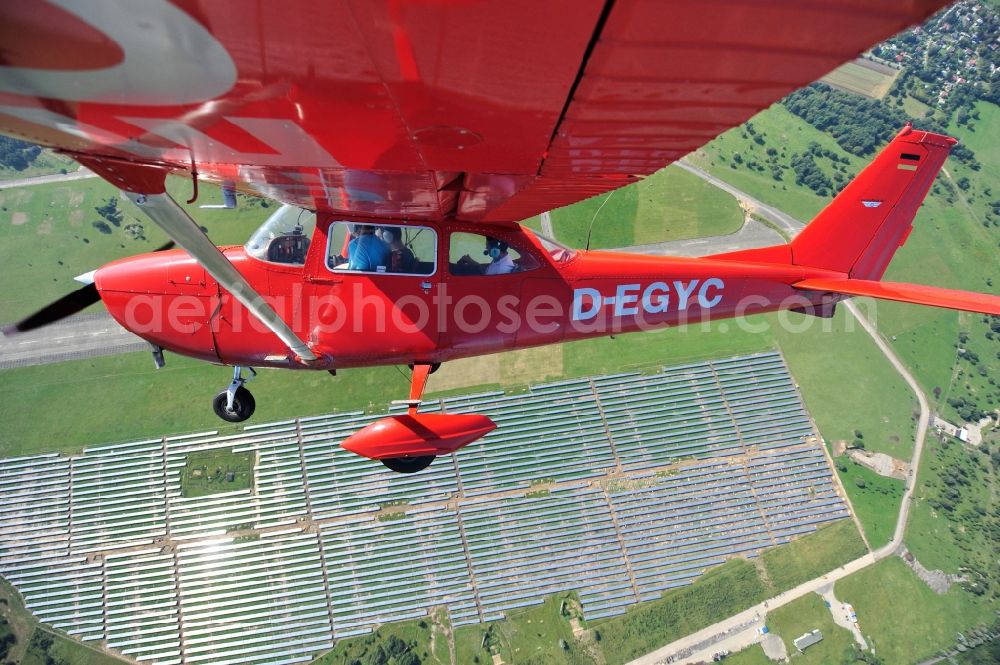 Werneuchen from the bird's eye view: Bright red Cessna 172 D-EGYC of the agency euroluftbild.de in flight over the airfield in Werneuchen in the state Brandenburg, Germany